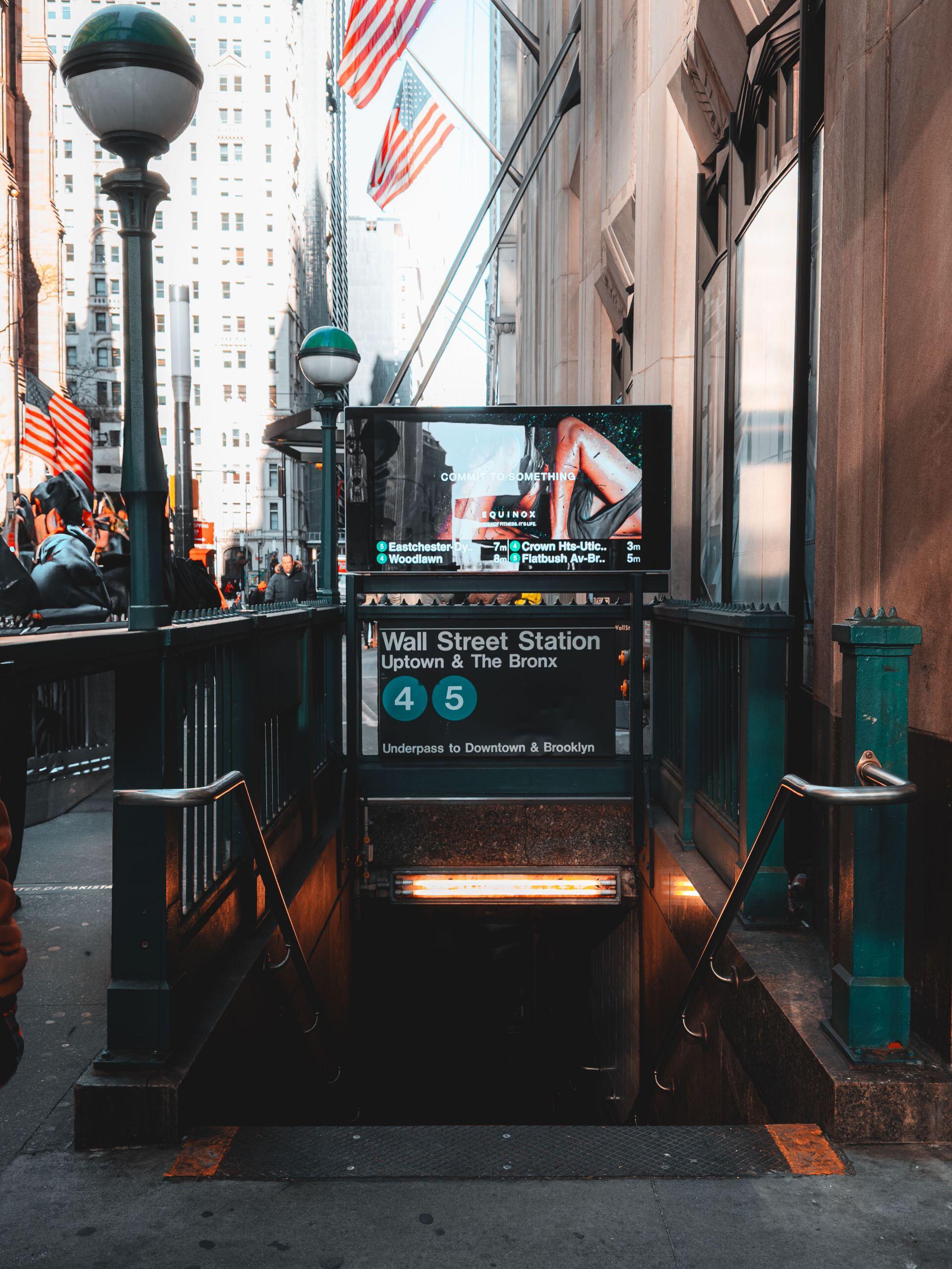 Wall Street, New York, entrada a la estación de subte con banderas de Estados Unidos, Pexels.