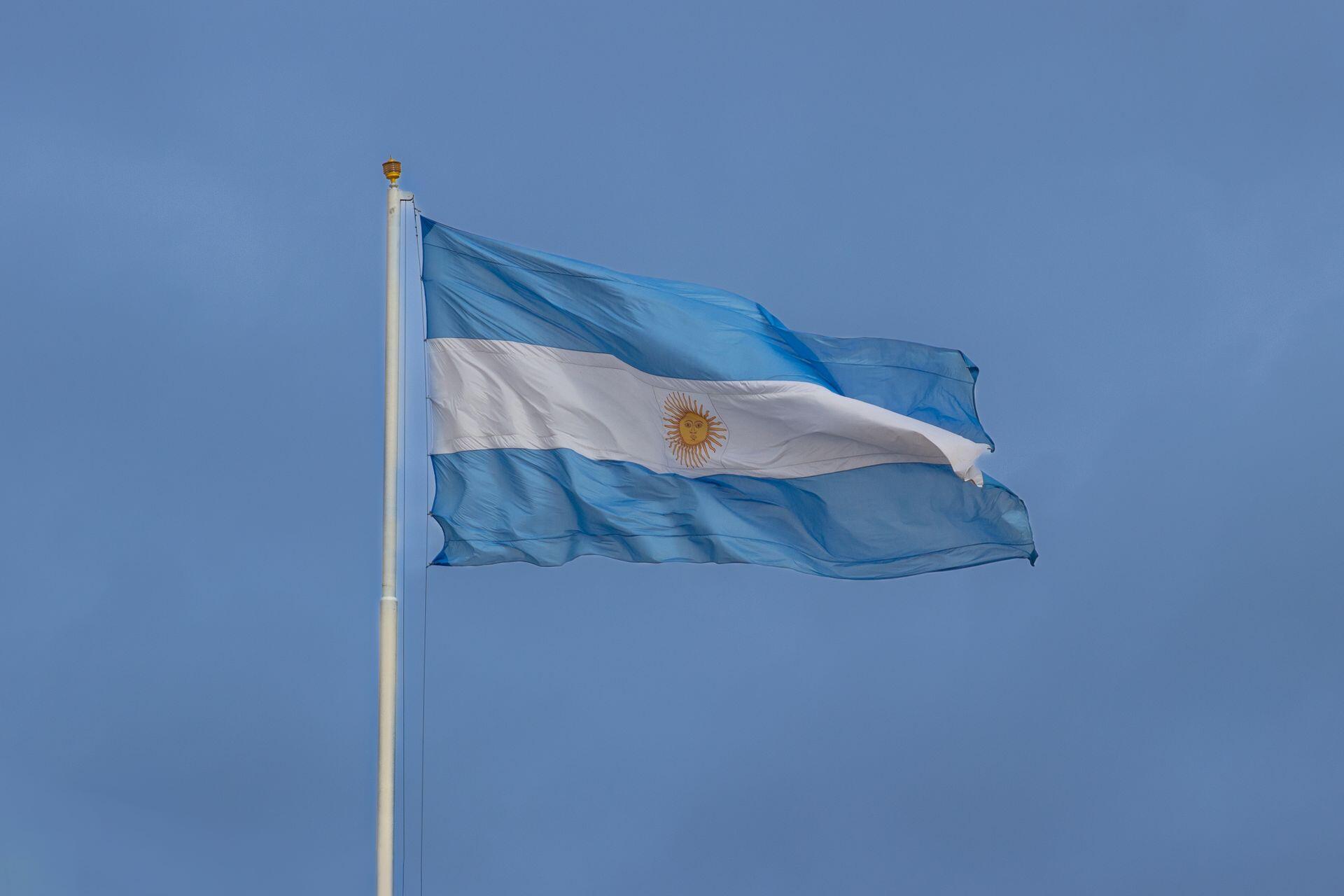 Bandera de argentina blanca y celeste flameando en el cielo azul.