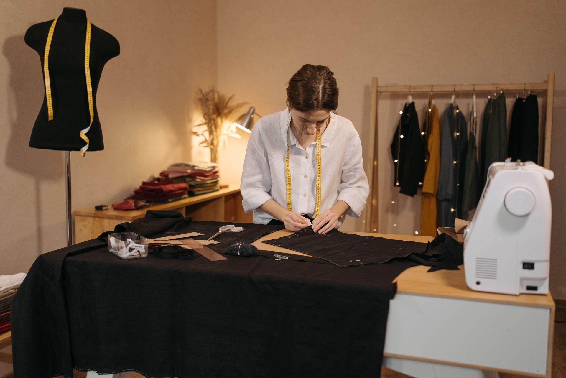Mujer cociendo en la habitación con ropa y maniquí negro.