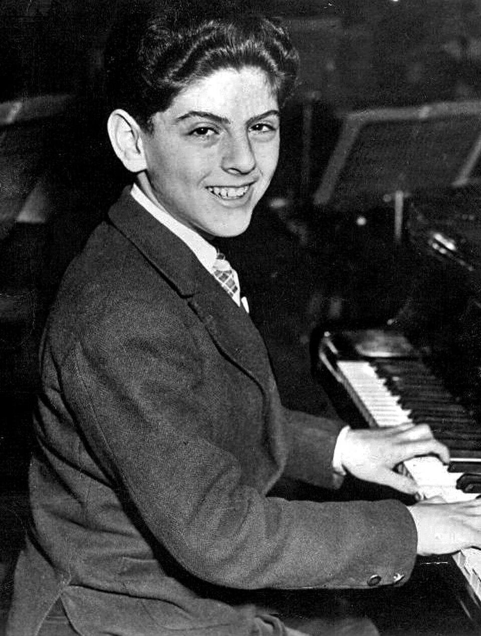 Foto blanco y negro de un niño sonriente tocando el piano.