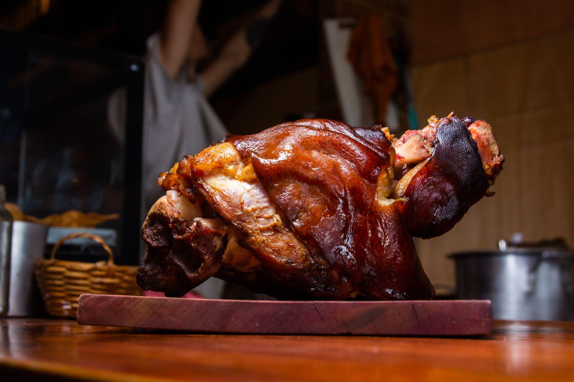 Bodegón alemán en CABA, codillo de cerdo asado sobre tabla de madera, Vinícius Caricatte.