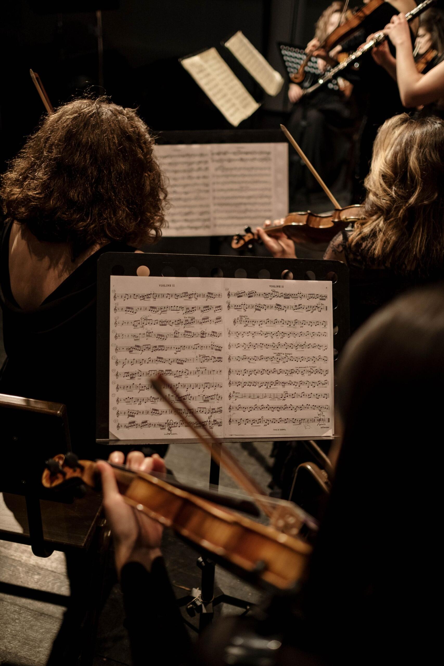 Musicos tocando el violín frente a las partituras.