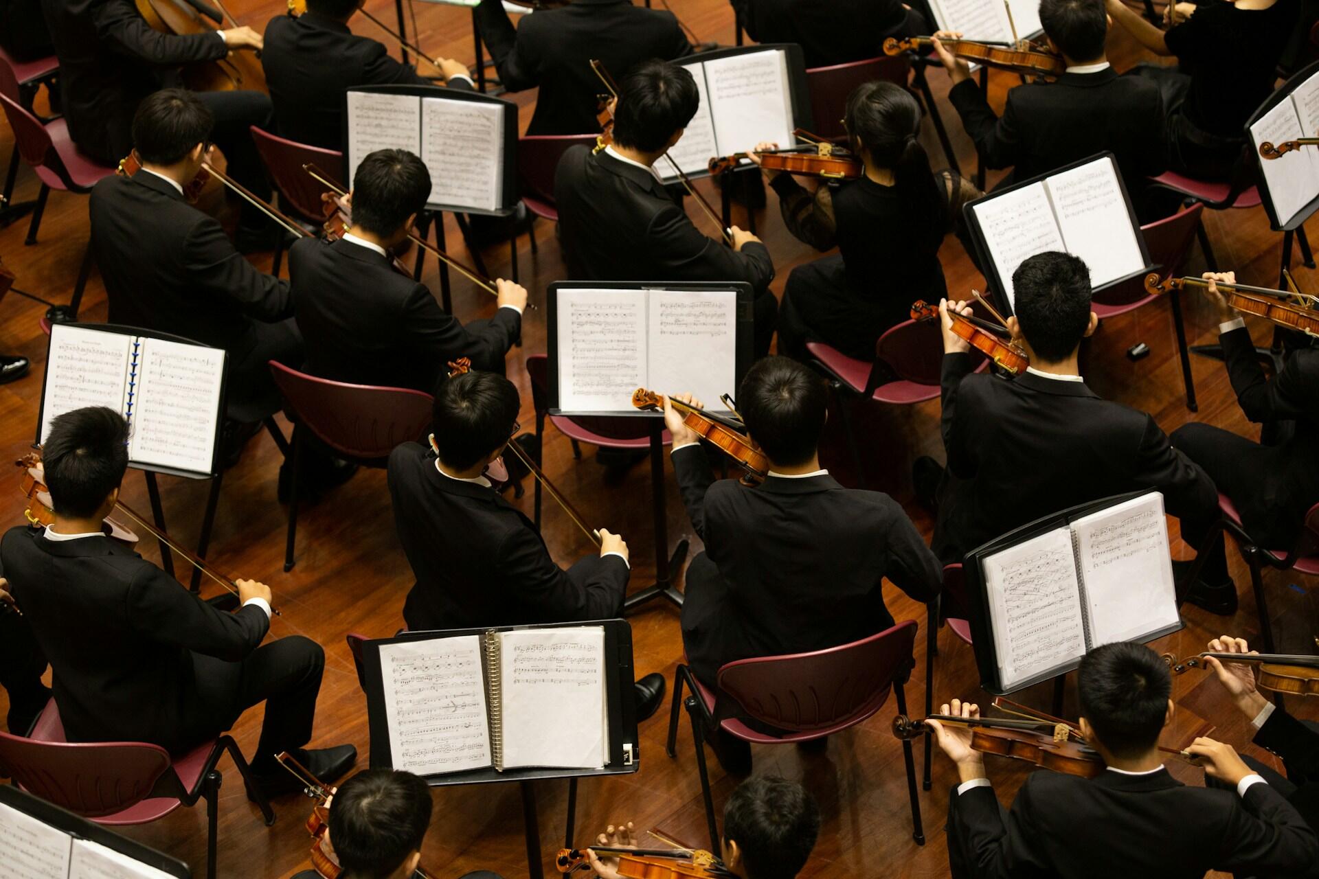 Orquesta tocando instrumentos y leyendo partituras musicales.