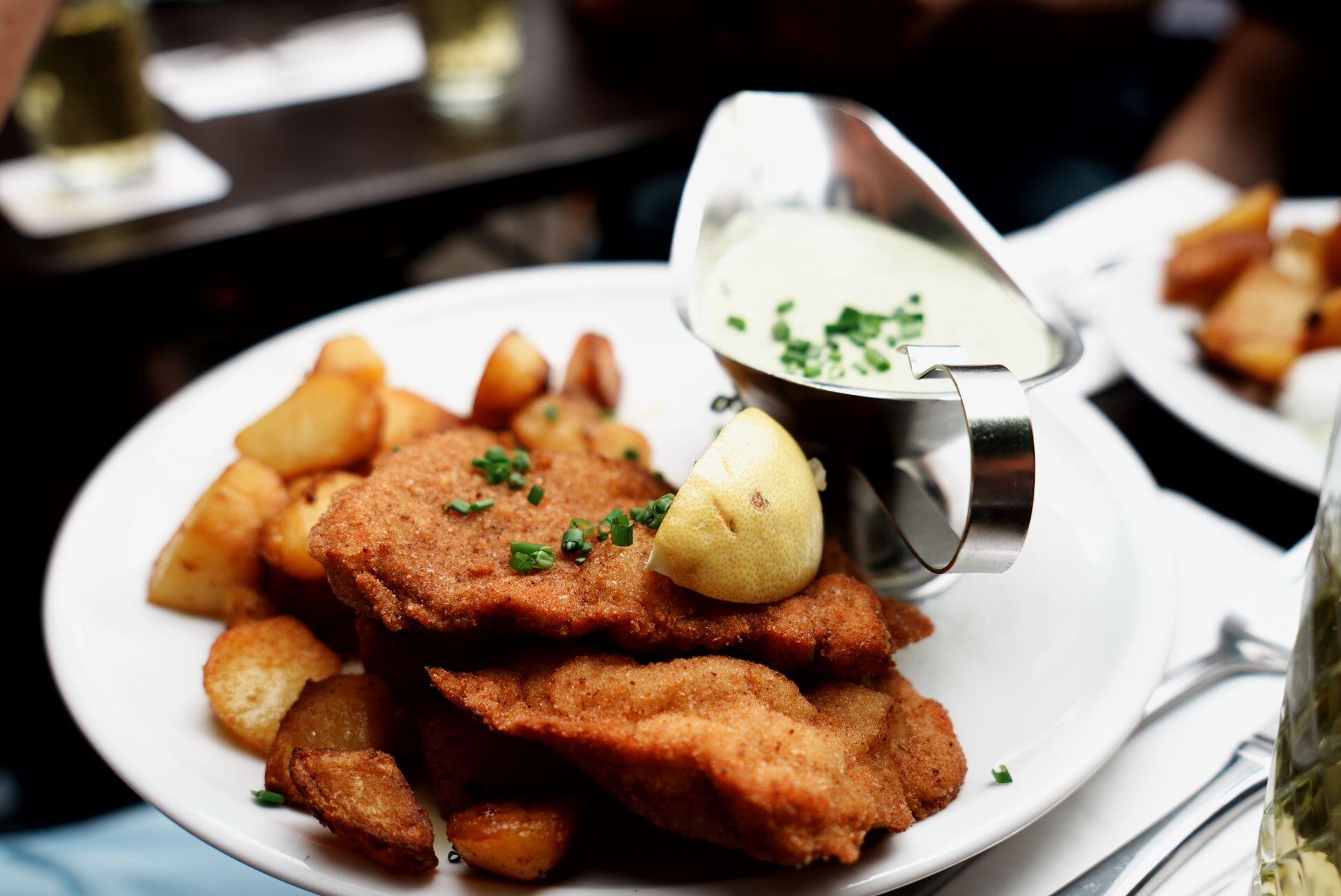 Restaurante alemán en Buenos Aires, plato de schnitzel con papas y salsa, Zhang Thomas.