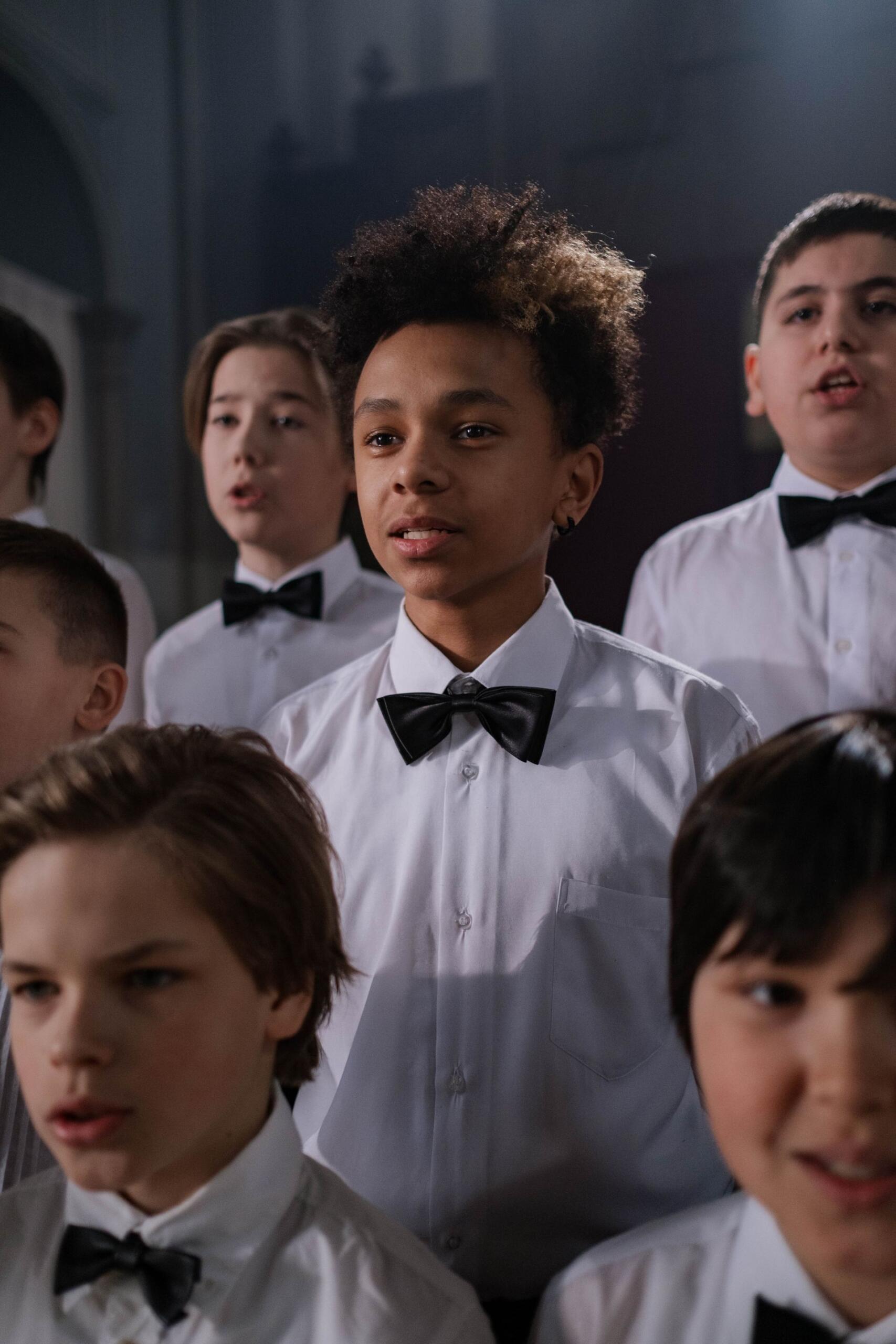 Interior de un auditorio con niños de un coro infantil uniformados practicando su dicción, por cottonbro studio.