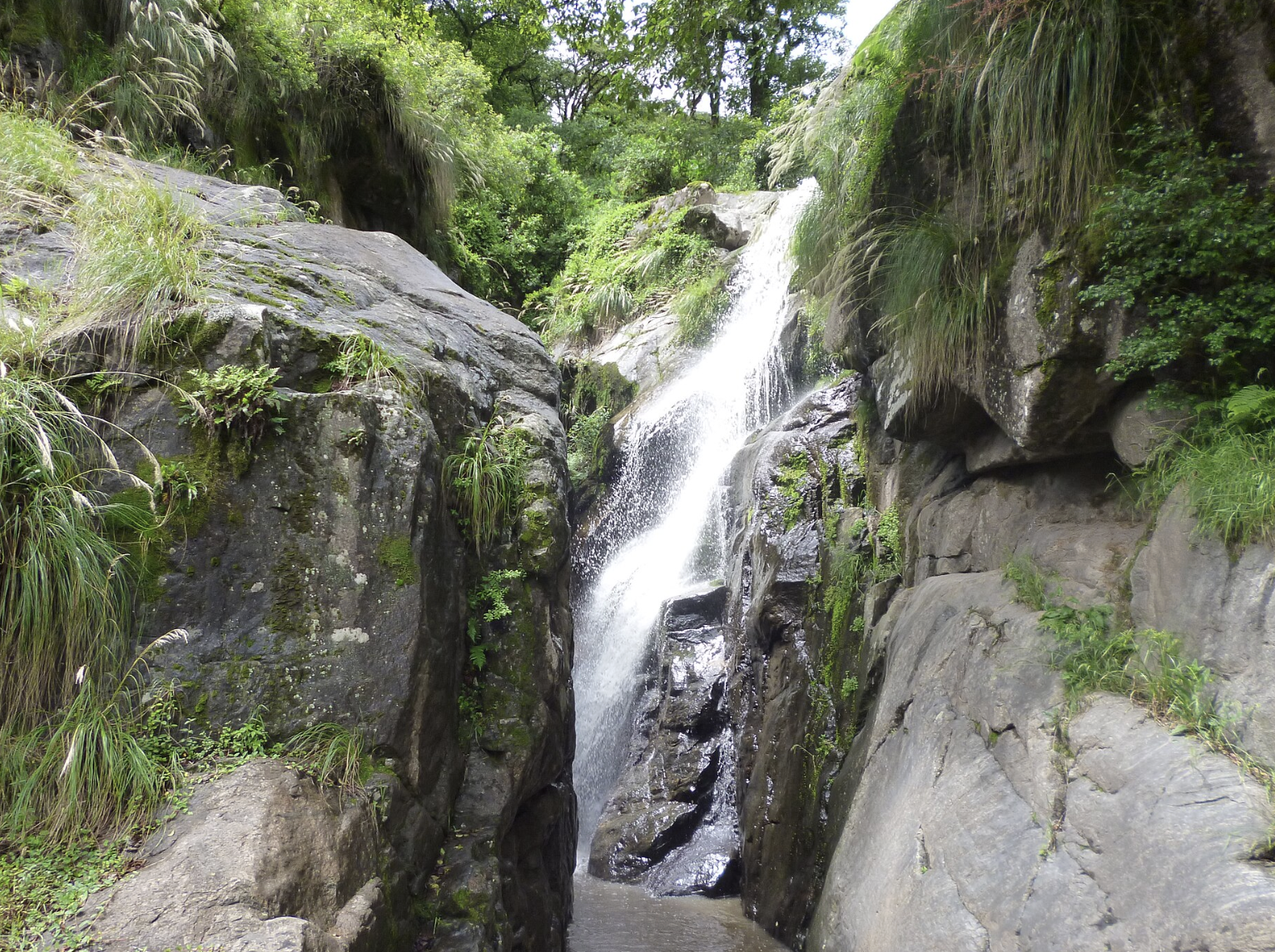 Cascada El Chorro, Tucumán: Salto de agua natural fluyendo entre grandes formaciones rocosas y musgo. Fuente: Wiki Commons.