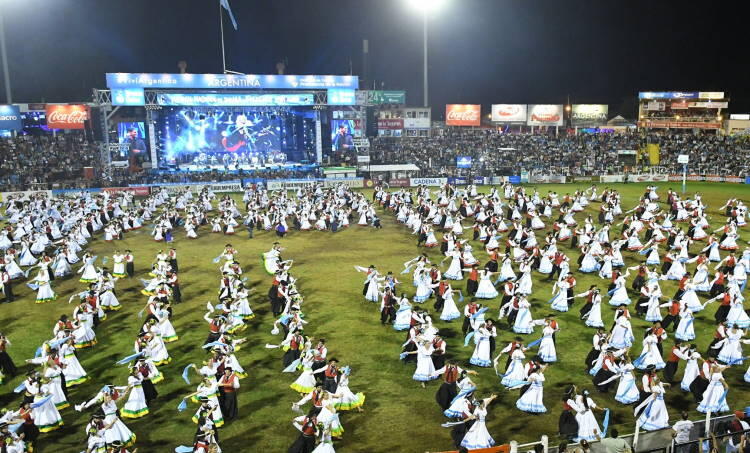 Personas bailando sobre el estadio delante de la pantalla.