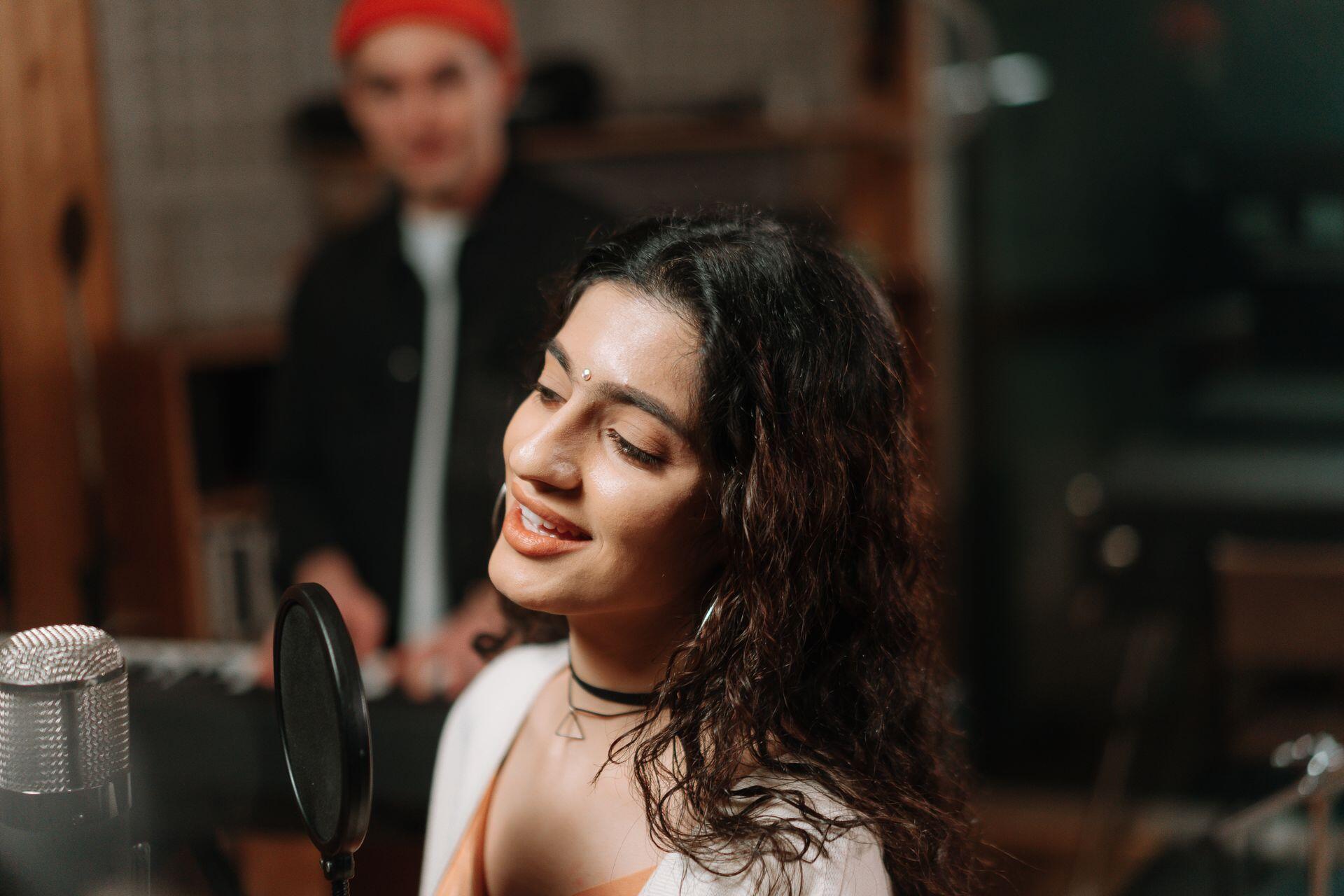 Estudio de grabación profesional con una mujer cantando frente a un micrófono de condensador, por cottonbro studio.
