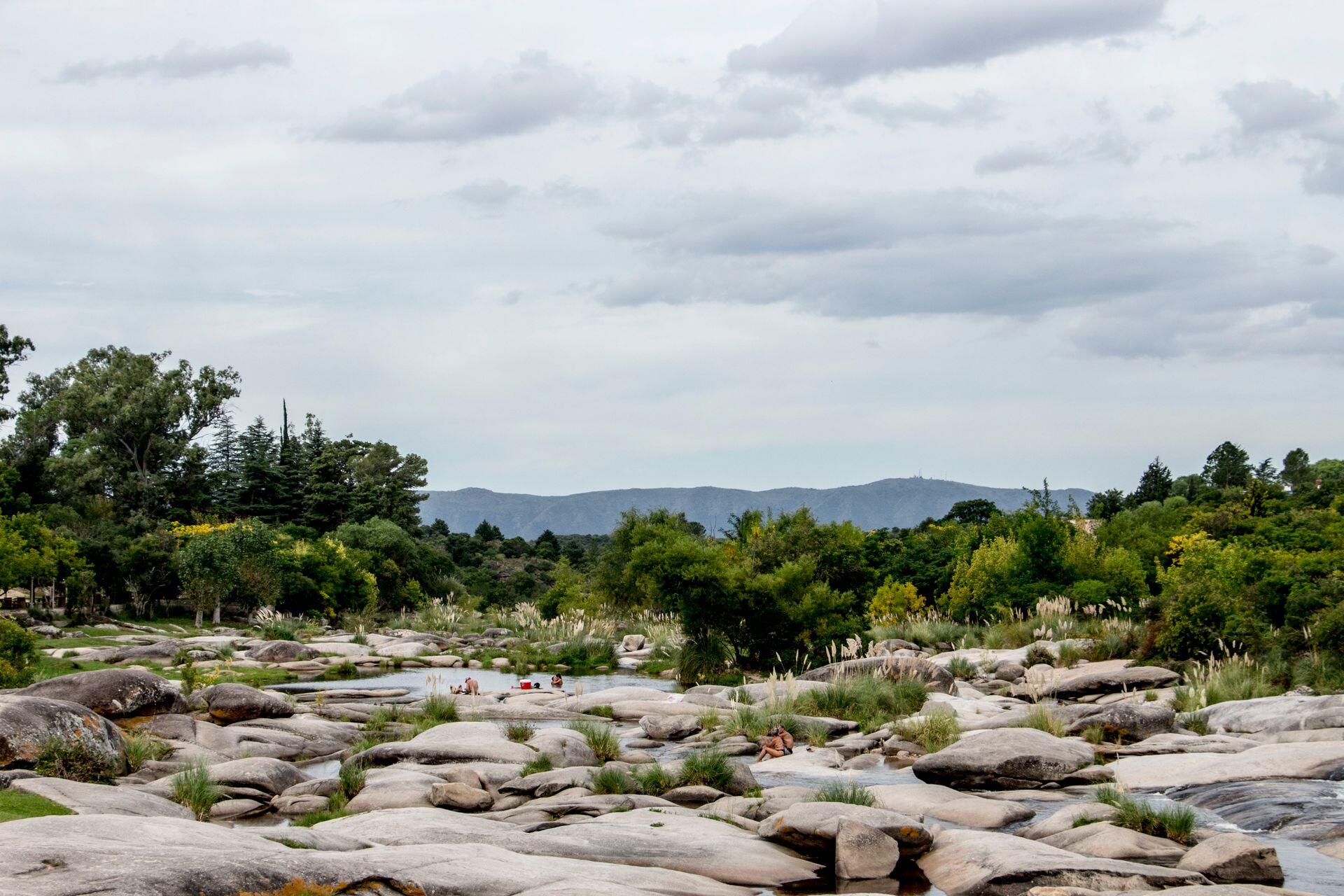 Paisaje de sierras, río y rocas entre la vegetación.