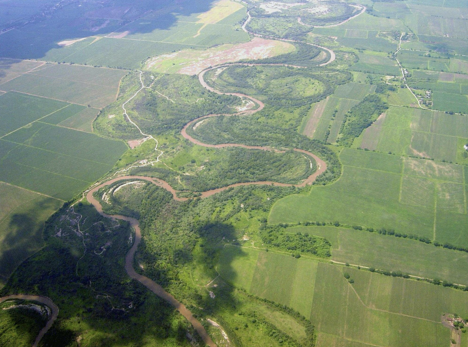 Río Salí, Tucumán: Vista aérea de los meandros del río serpenteando entre campos de cultivo verdes. Fuente: Wiki Commons.