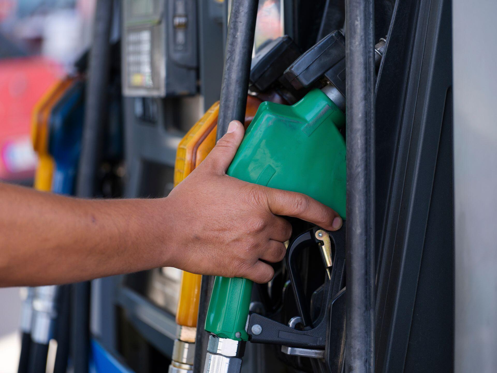 Mano sosteniendo el surtidor de combustible verde.