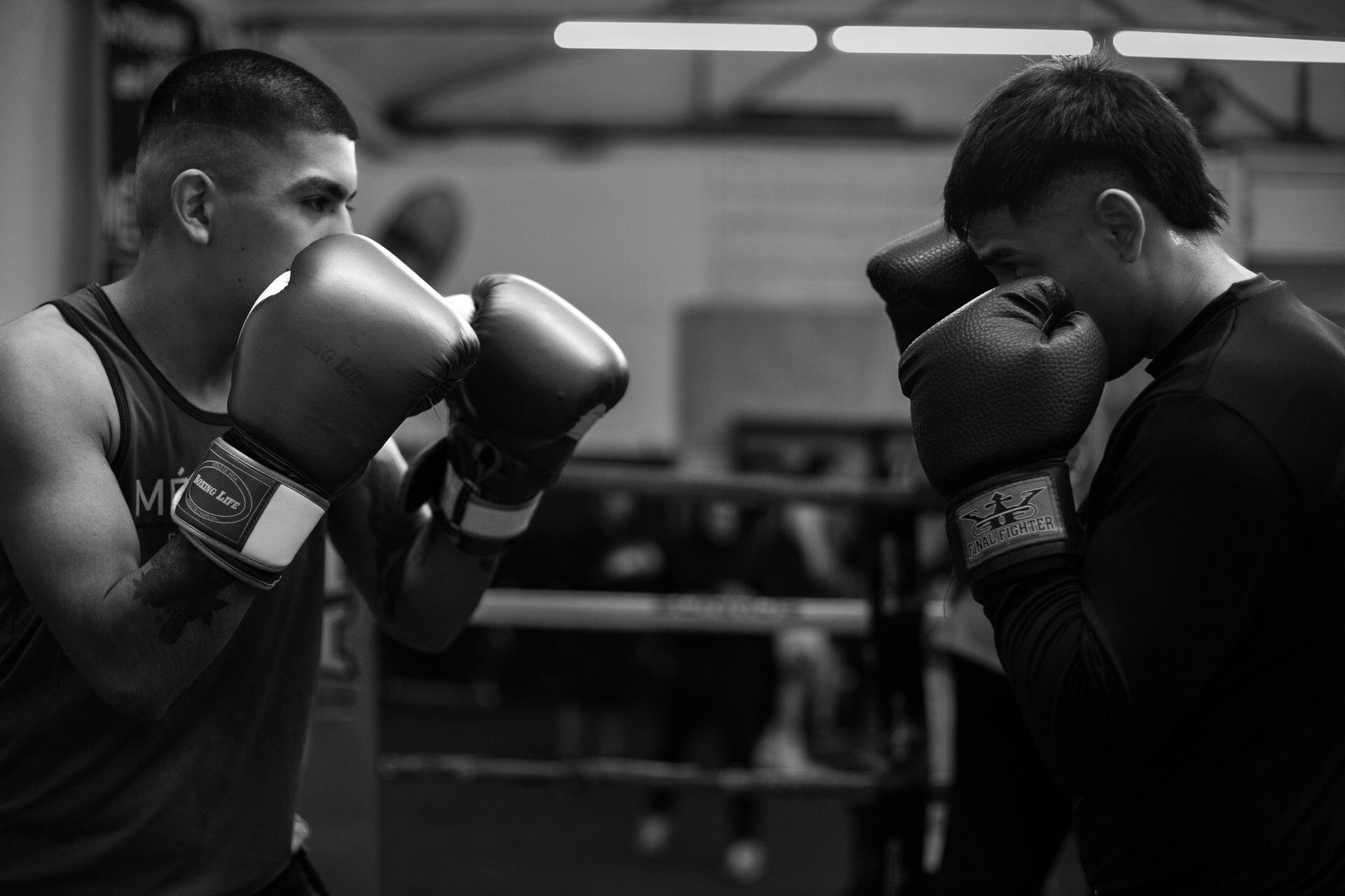 Hombres enfrentados en el rin con guantes de boxeo.