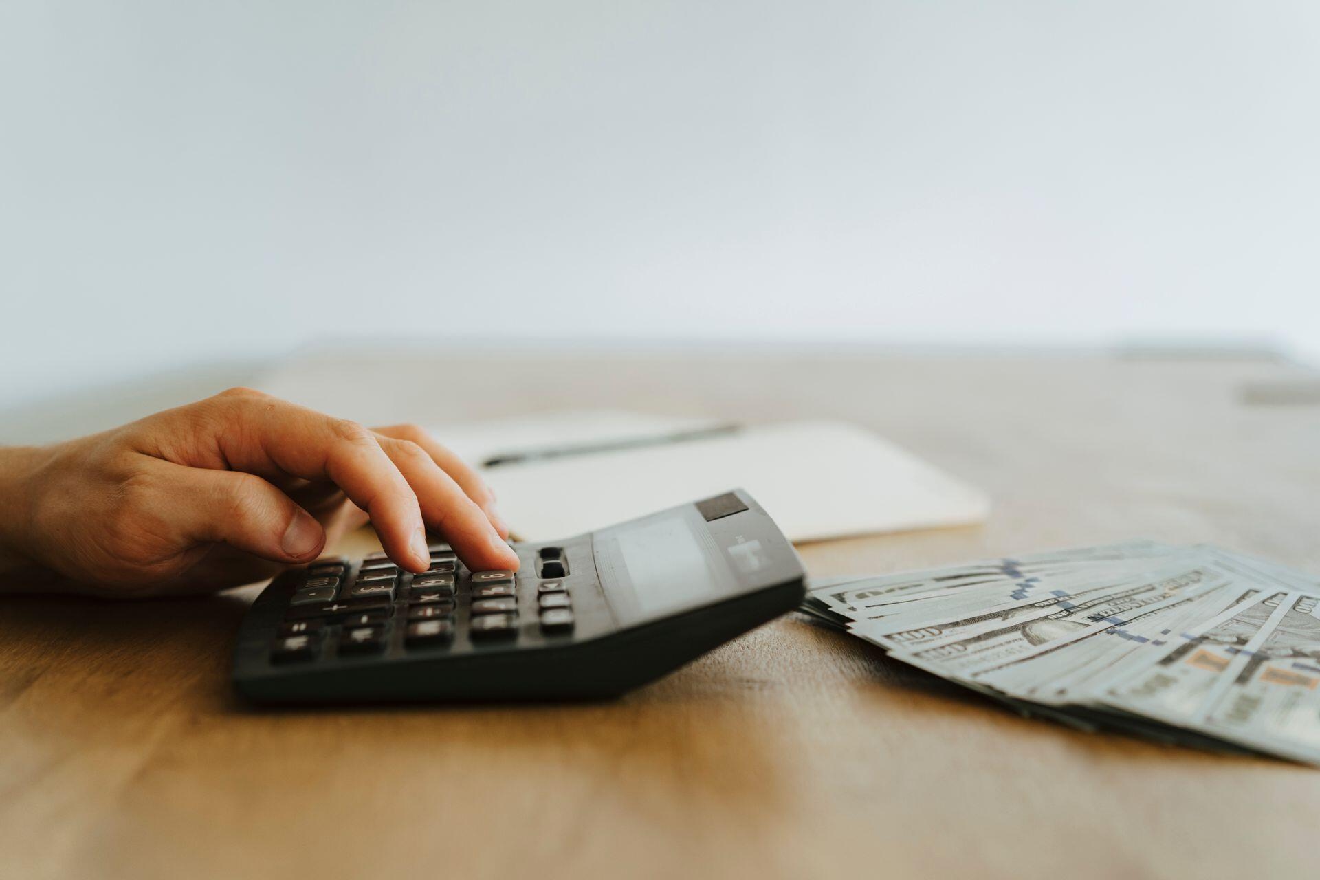 Calculadora y billetes sobre la mesa de madera.