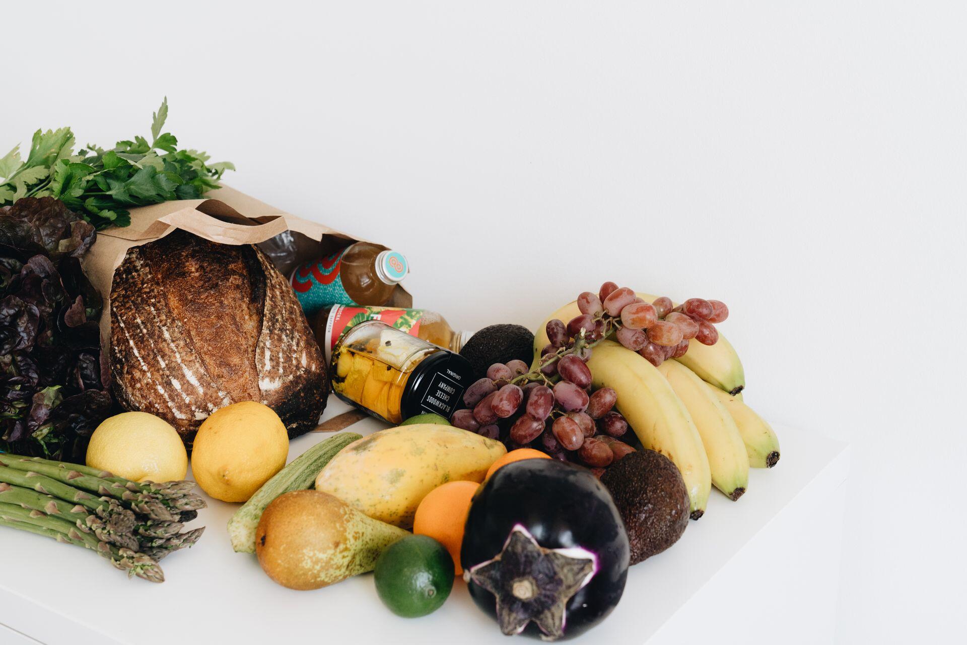 Vegetales y bolsa de alimentos deplegada sobre la superficie blanca.