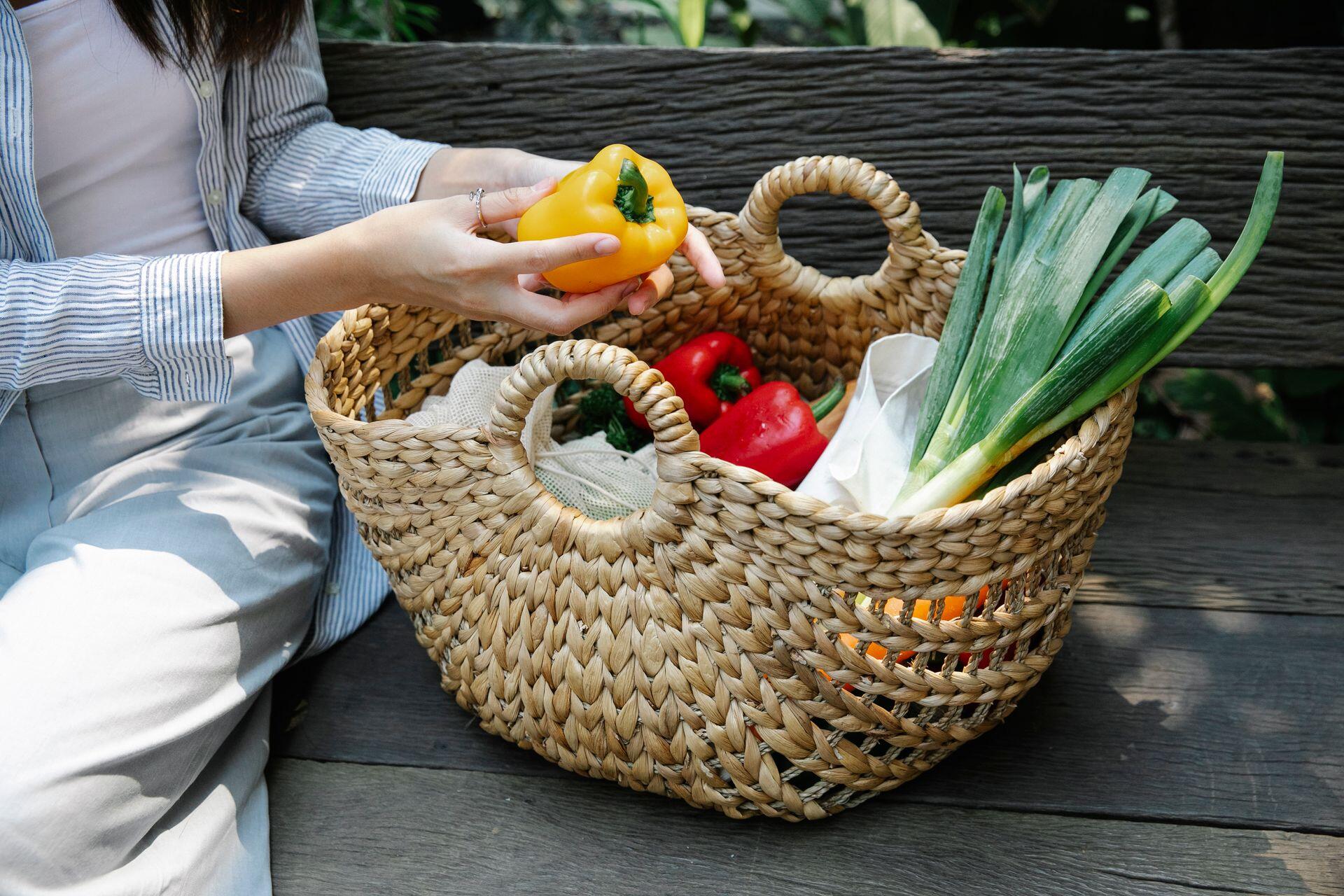 Canasta de mimbre con verduras adentro.