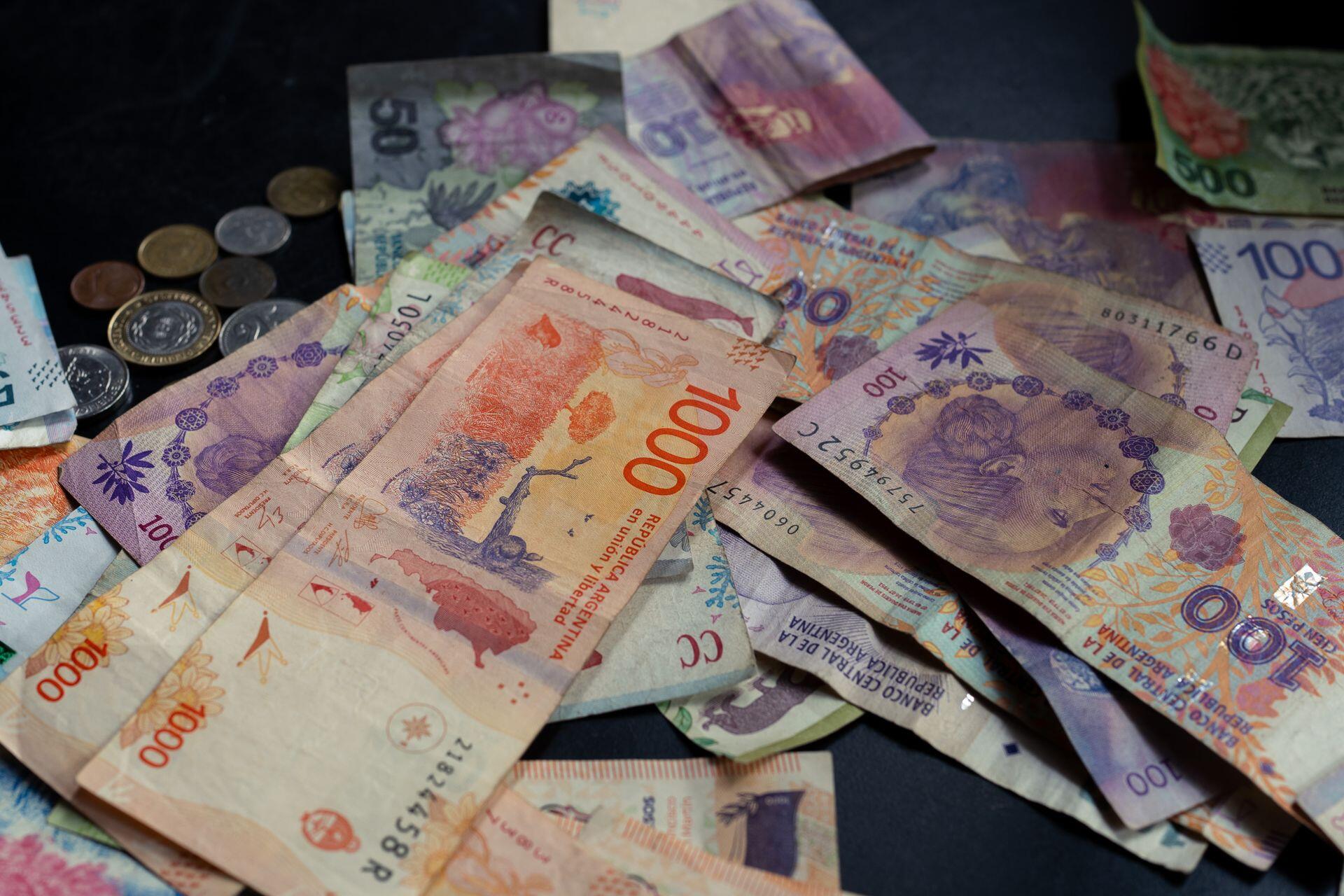 Billetes y monedas apotados sobre la superficie negra.