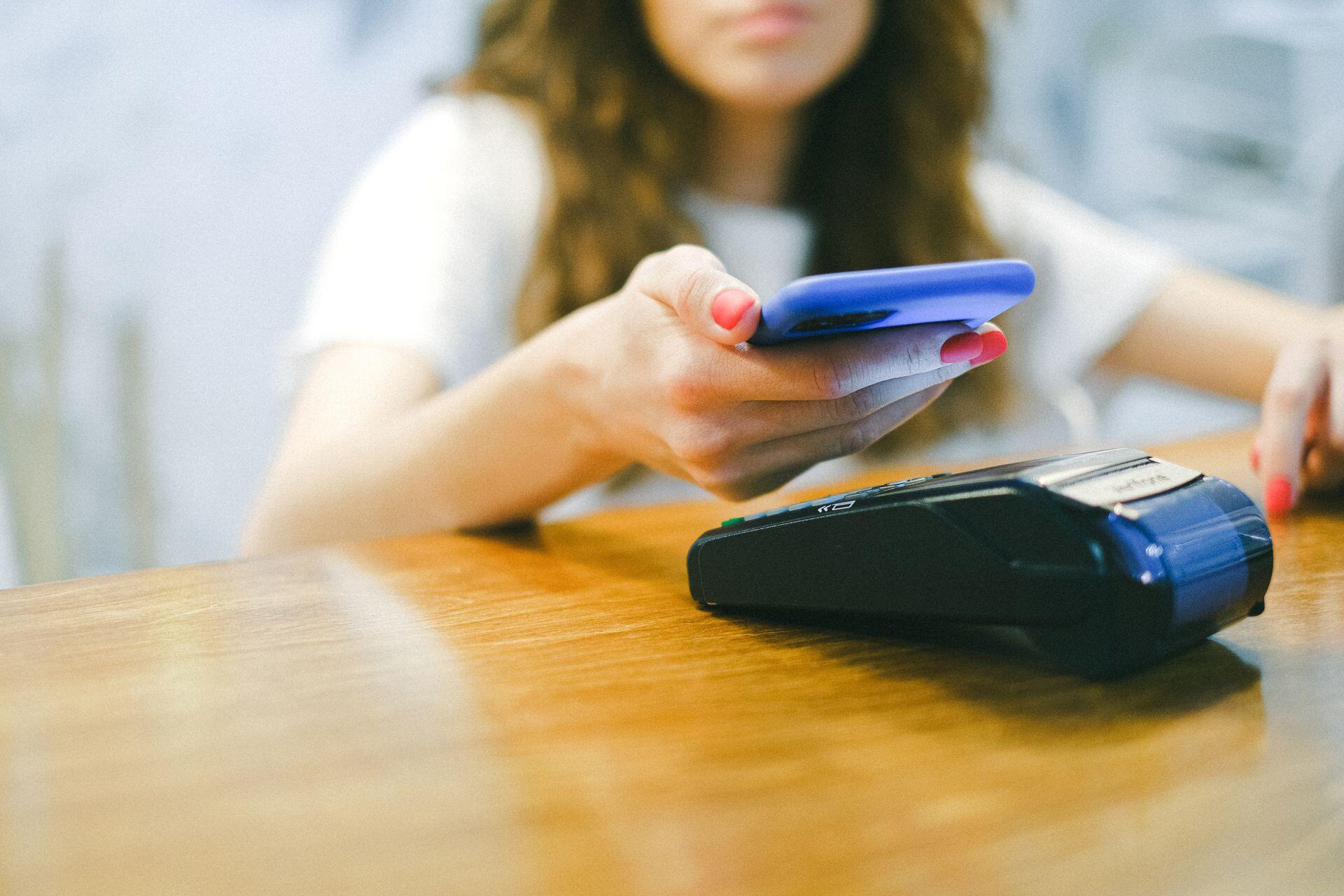 Mujer pagando en el postnet con el celular.