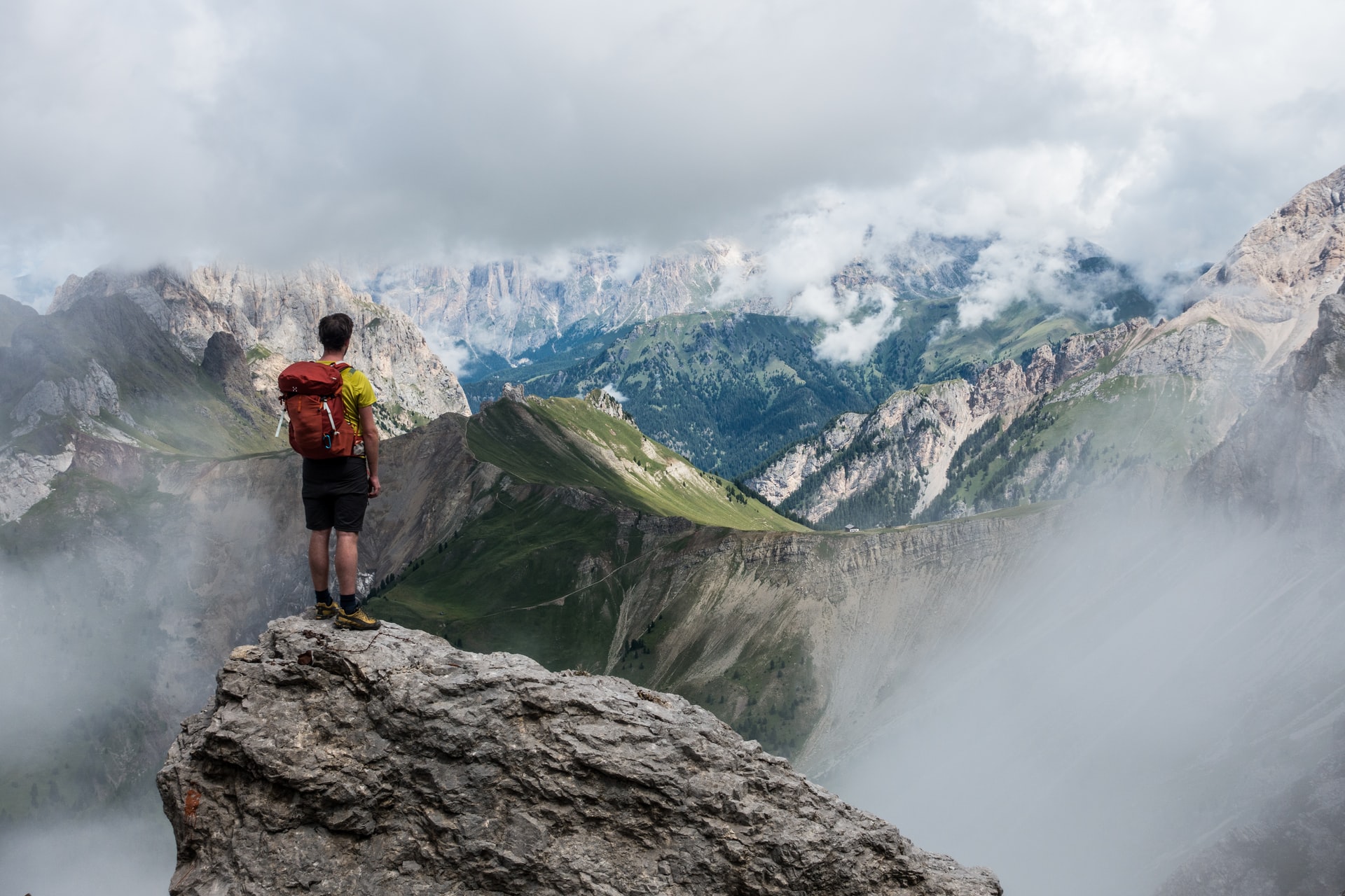 Ein Mann genießt die Aussicht auf dem Berg nach dem er diesen erklommen hat.