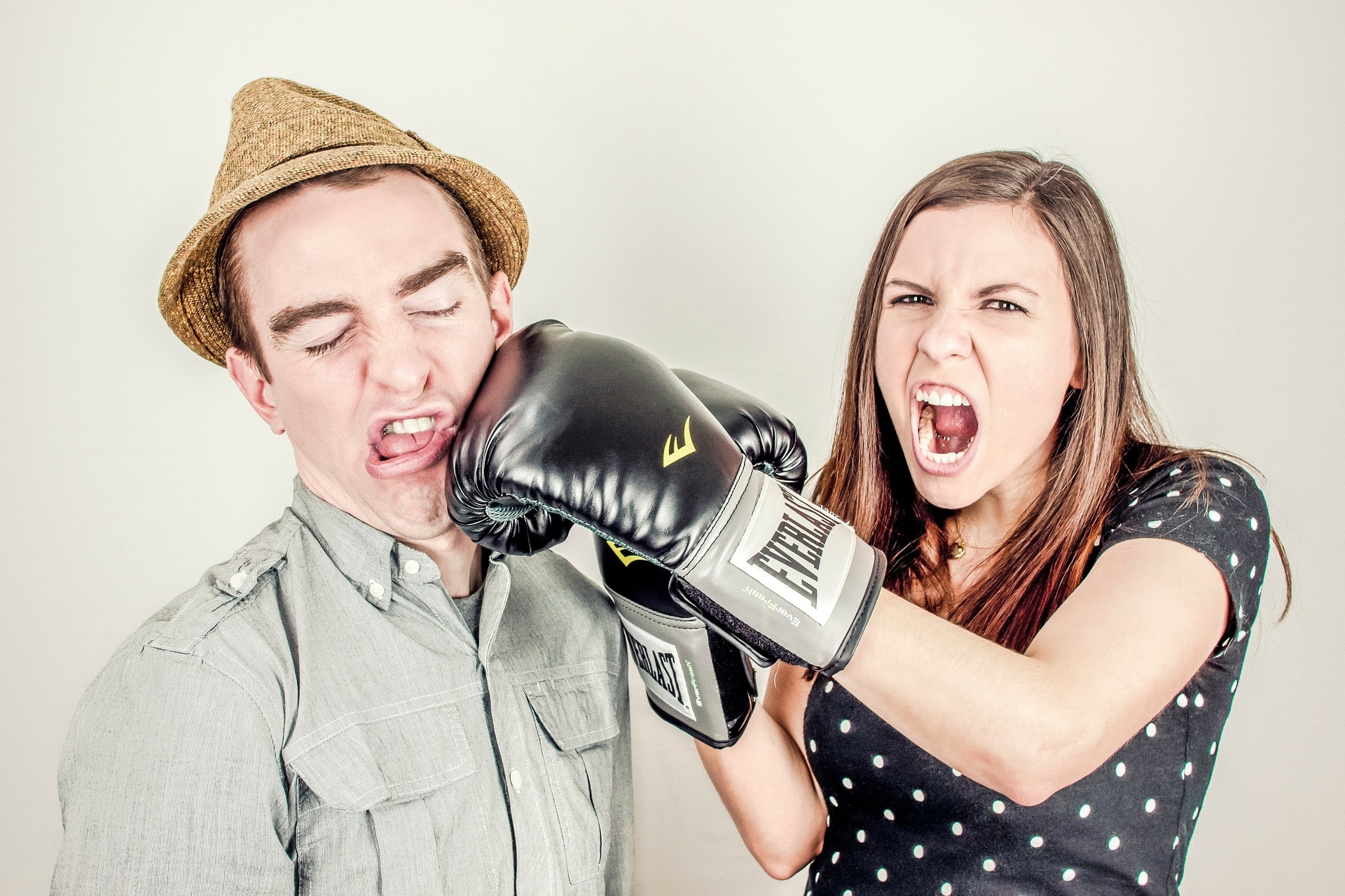 Eine Frau schlägt einem Mann mit einem Boxhandschuh verärgert in das Gesicht.