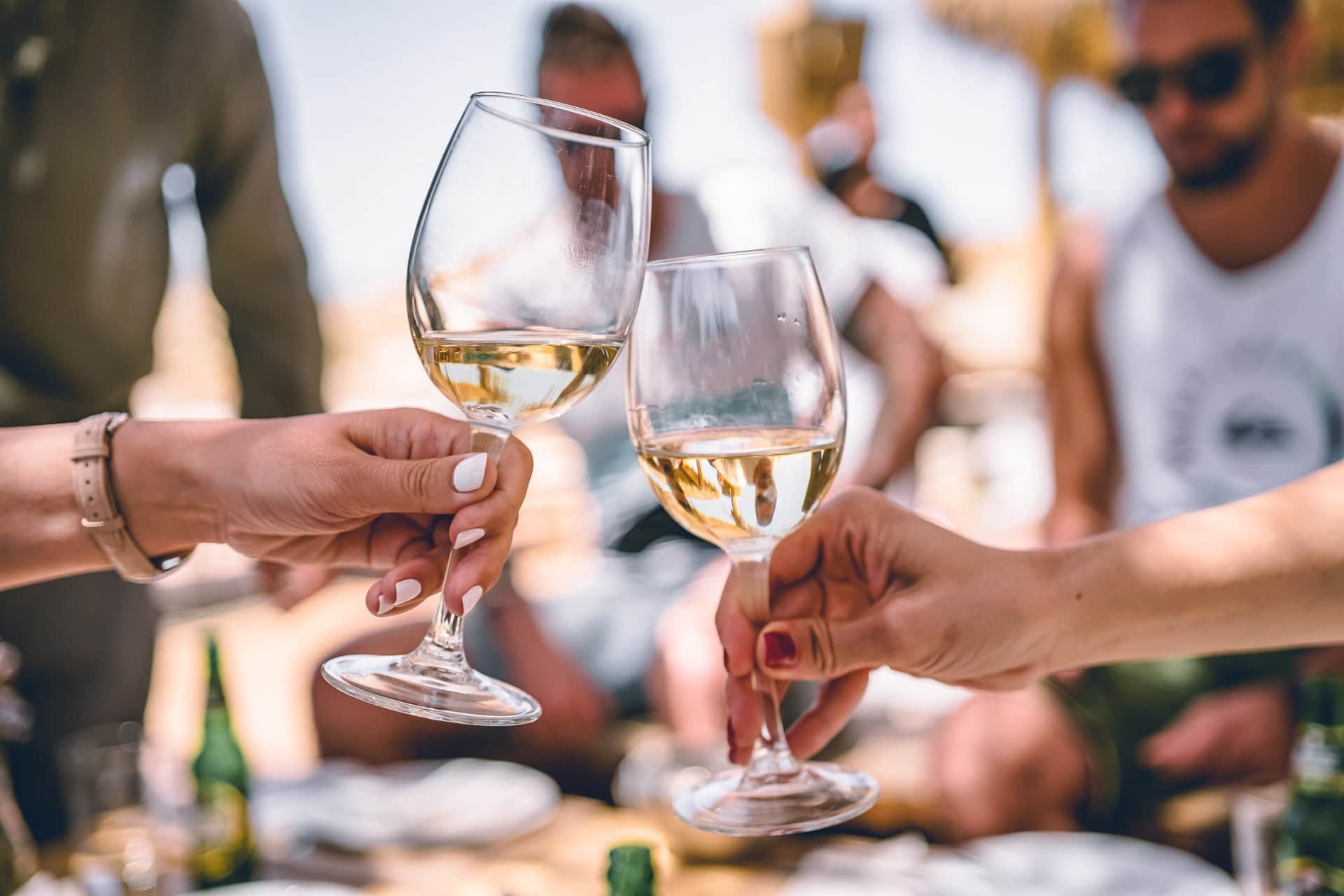 Zwei Freunde stoßen mit einem Glas Weißwein an.