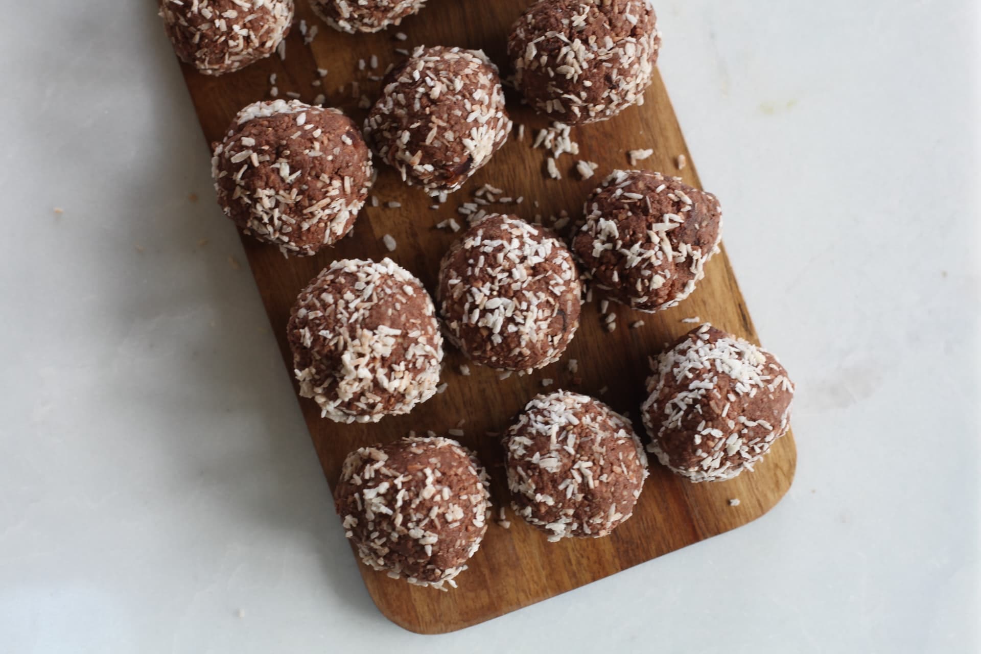 Energy Balls mit Kakao und Kokosflocken auf braunem Brett