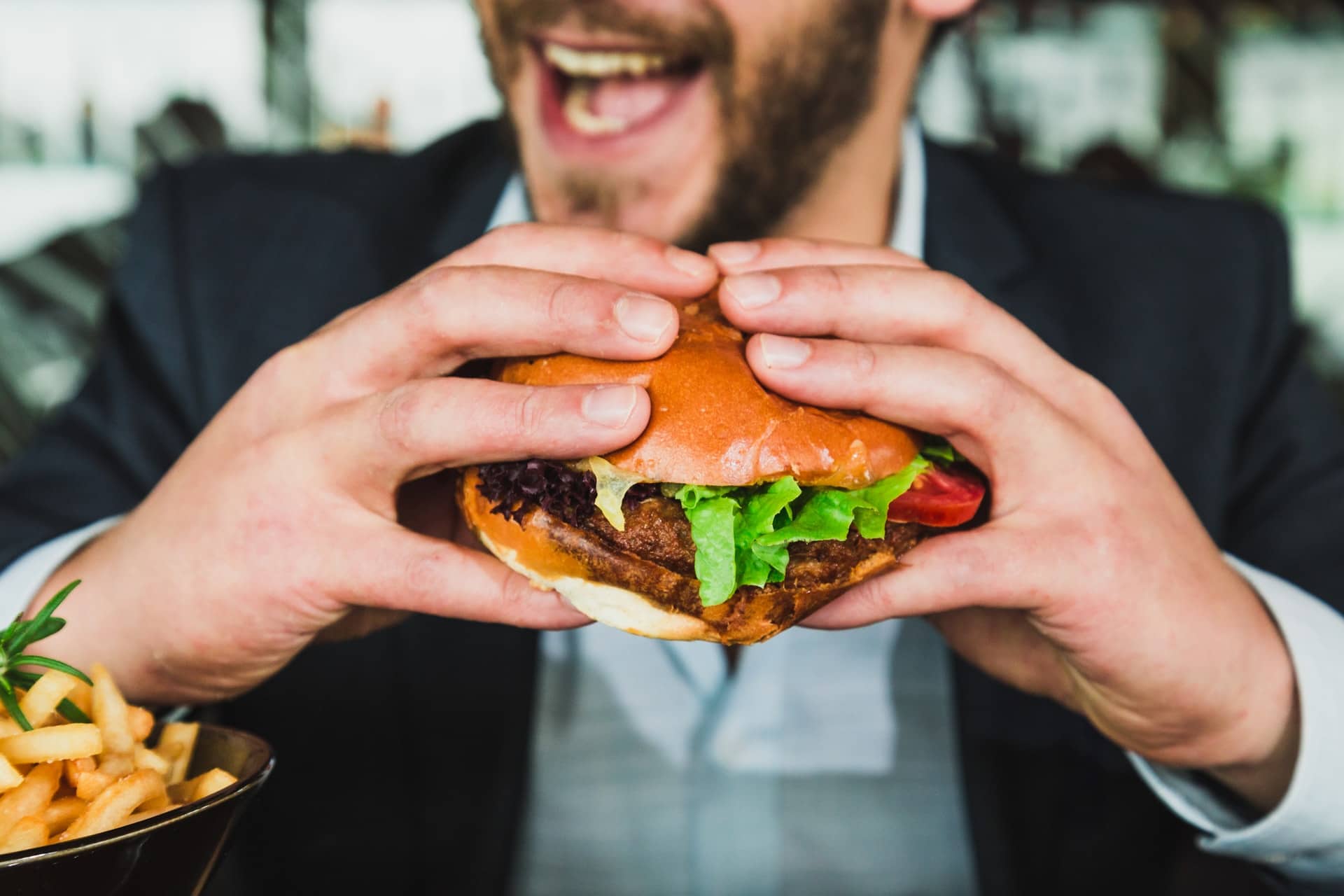 Mann mit dunklem Bart ist dabei Burger zu essen