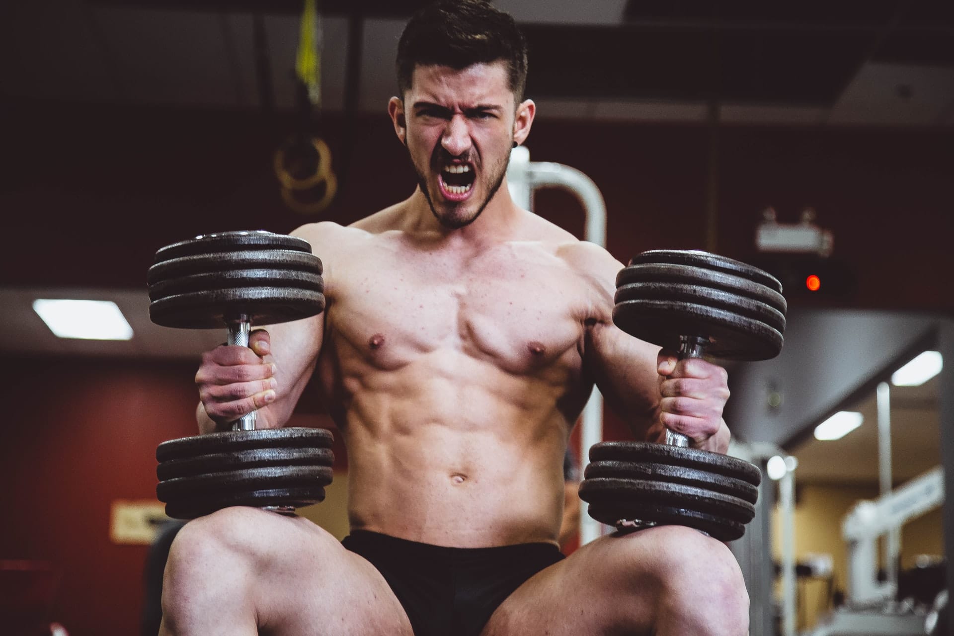 Ein Mann trainiert mit Gewichten im Fitnessstudio.