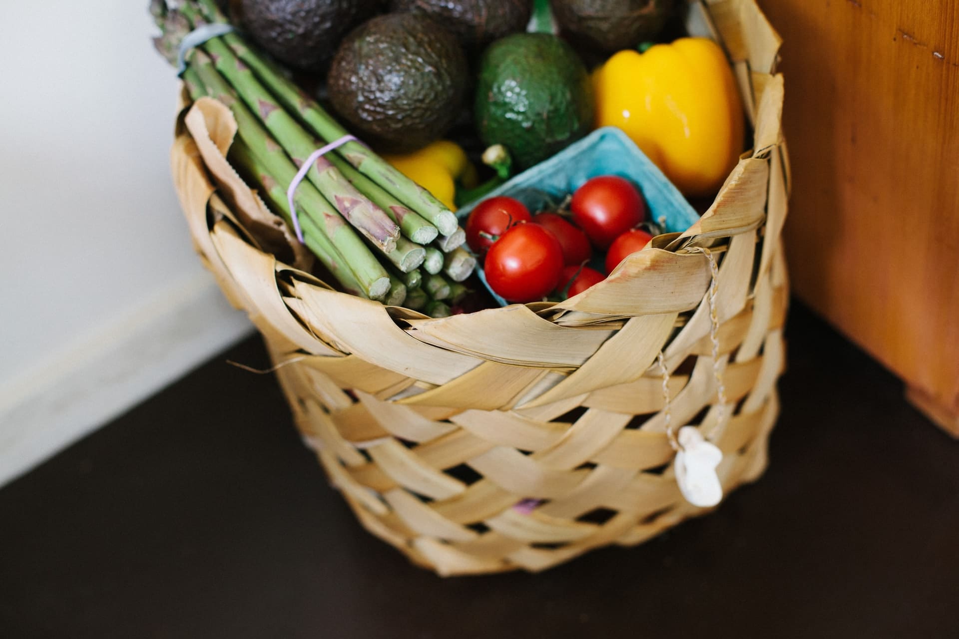 Verschiedene Gemüsesorten wie Tomaten Spargel Paprika und Avocados liegen in einem Korb