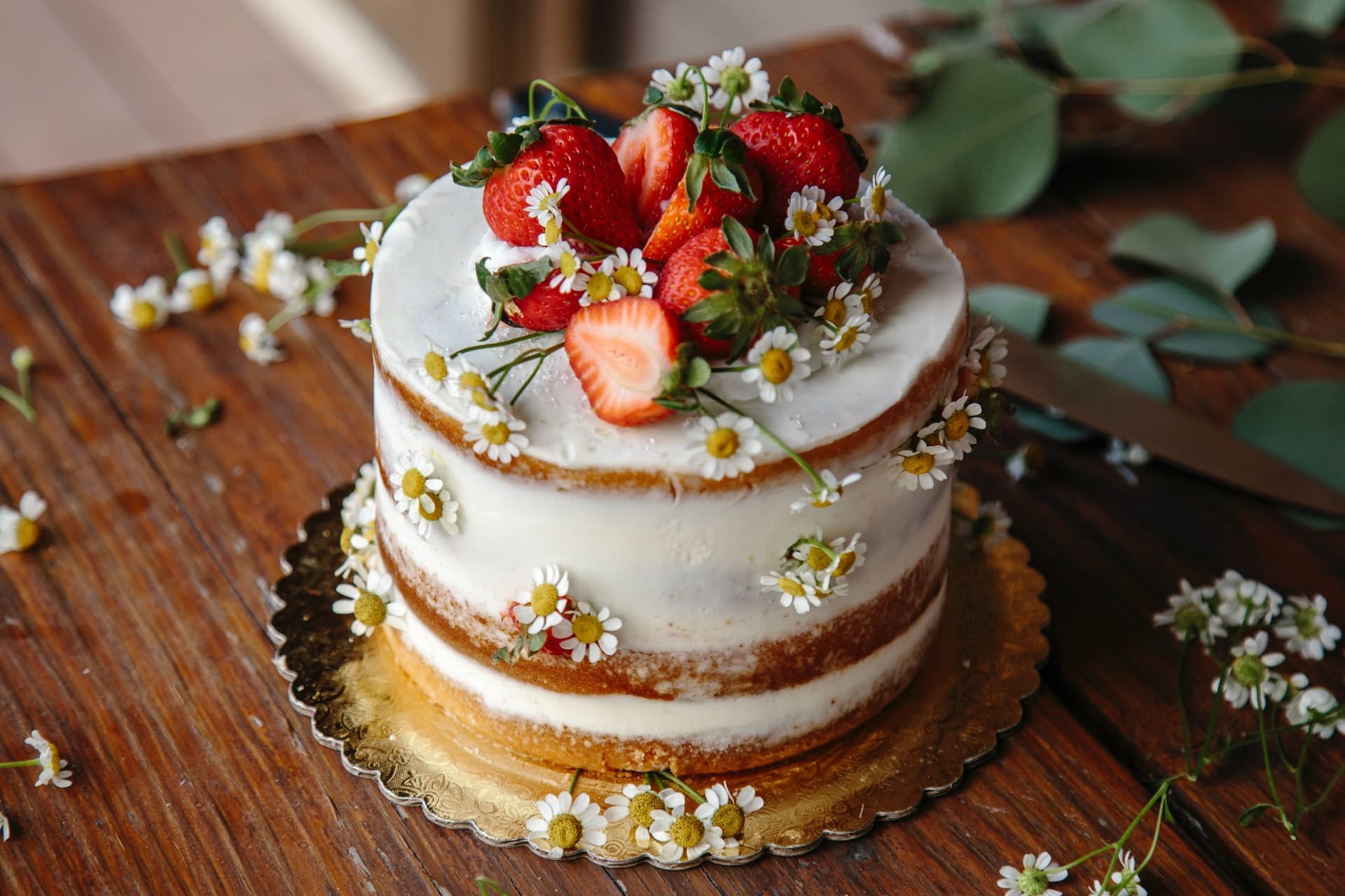Schön dekorierte Torte mit weißer Glasur Erdbeeren und Gänseblümchen