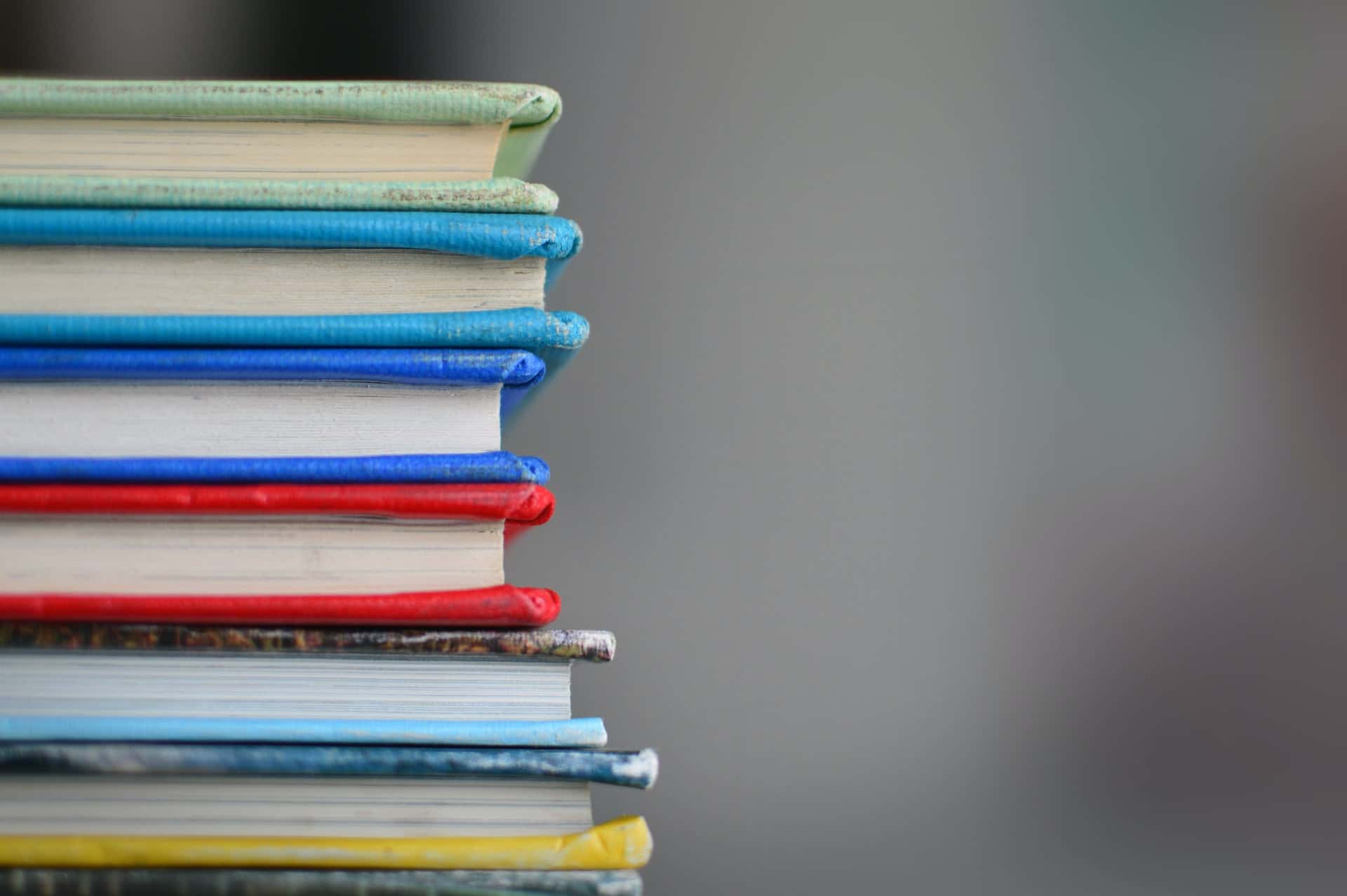 Bunte Bücher liegen aufeinander gestapelt vor verschwommenen Hintergrund