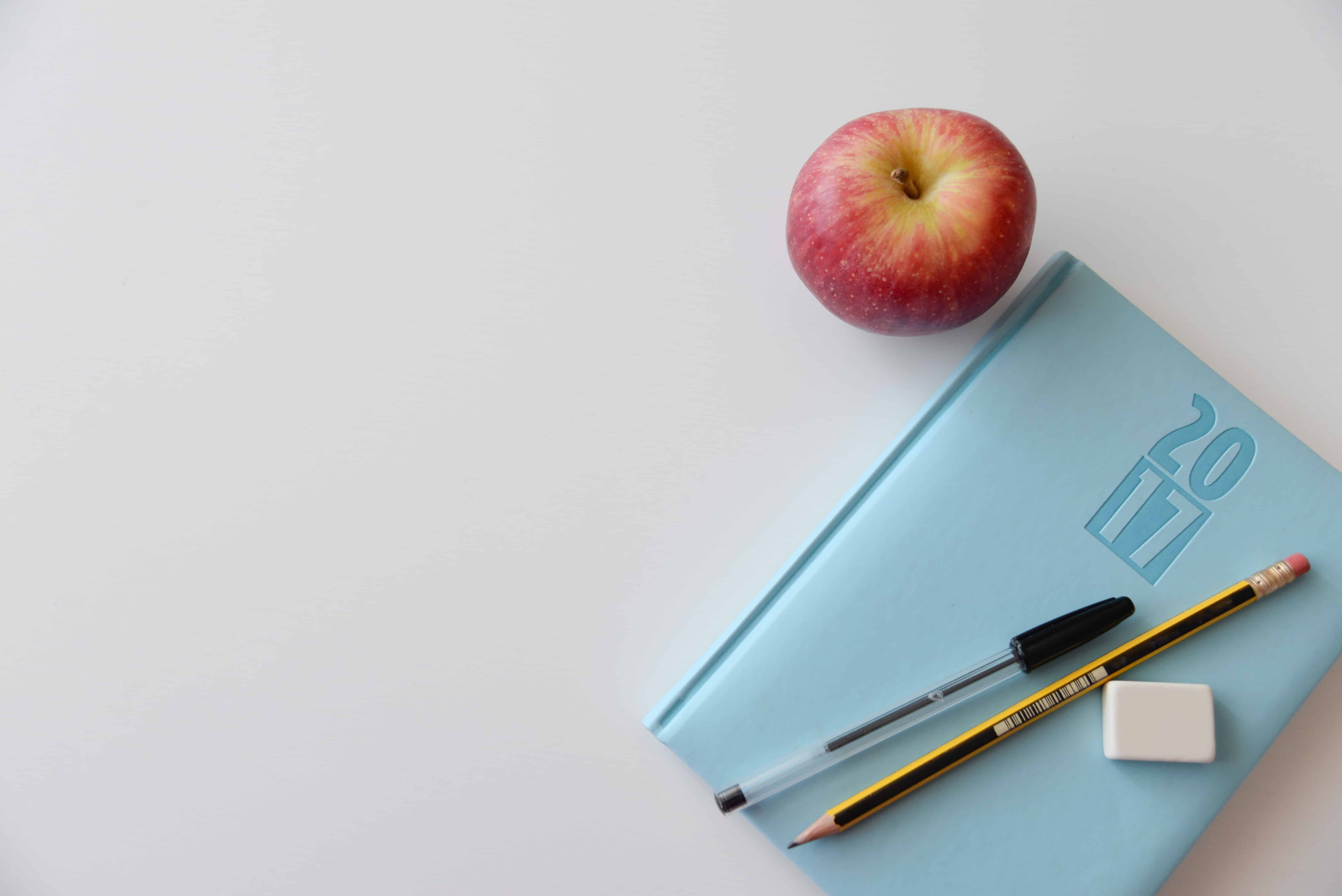 Blauer Terminkalender mit Stiften und Apfel
