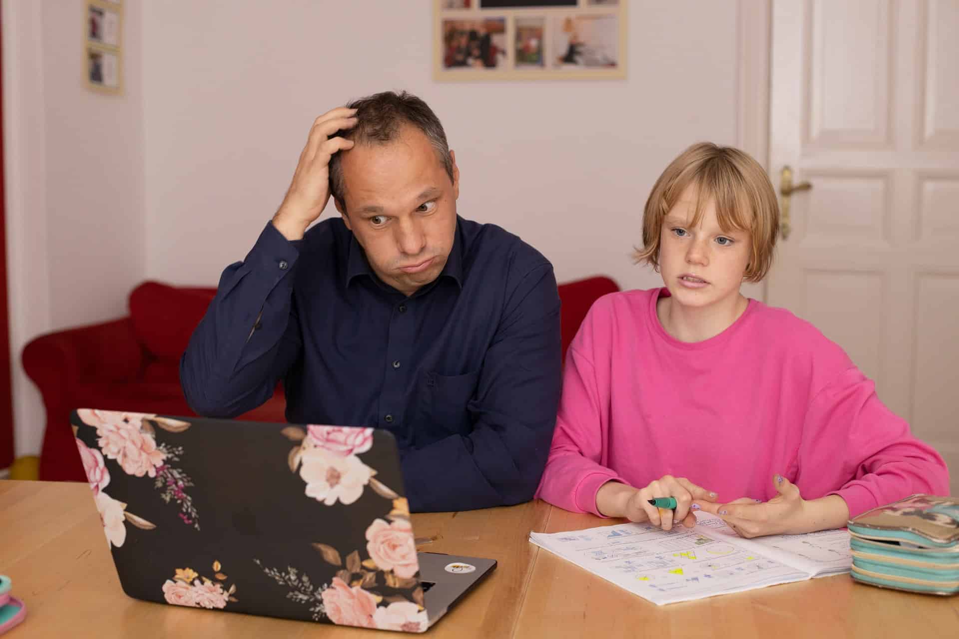Vater und Tochter sitzen vor Laptop