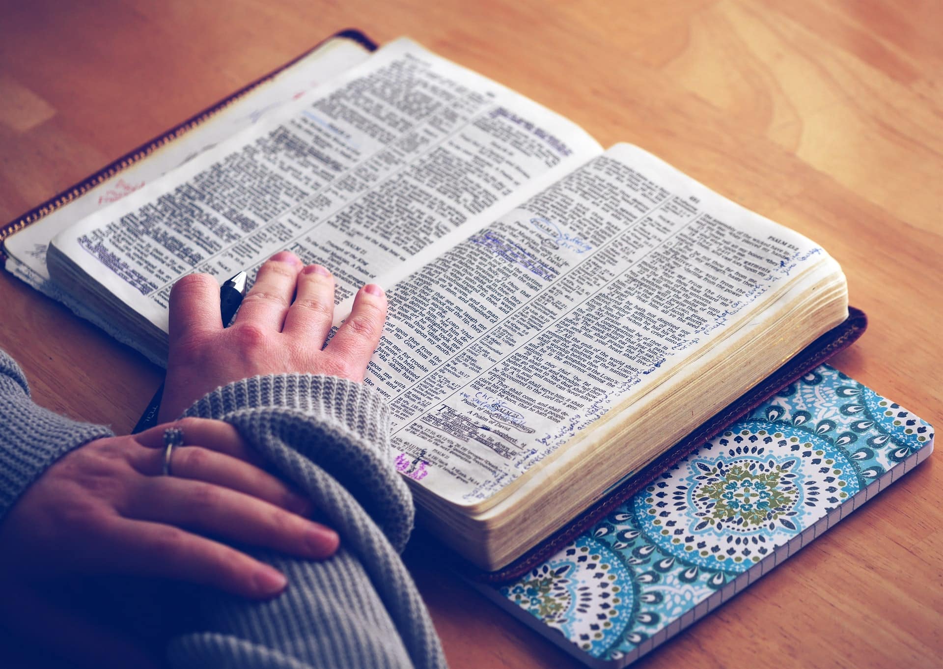Person sitzt an Tisch und schlägt Wörterbuch auf