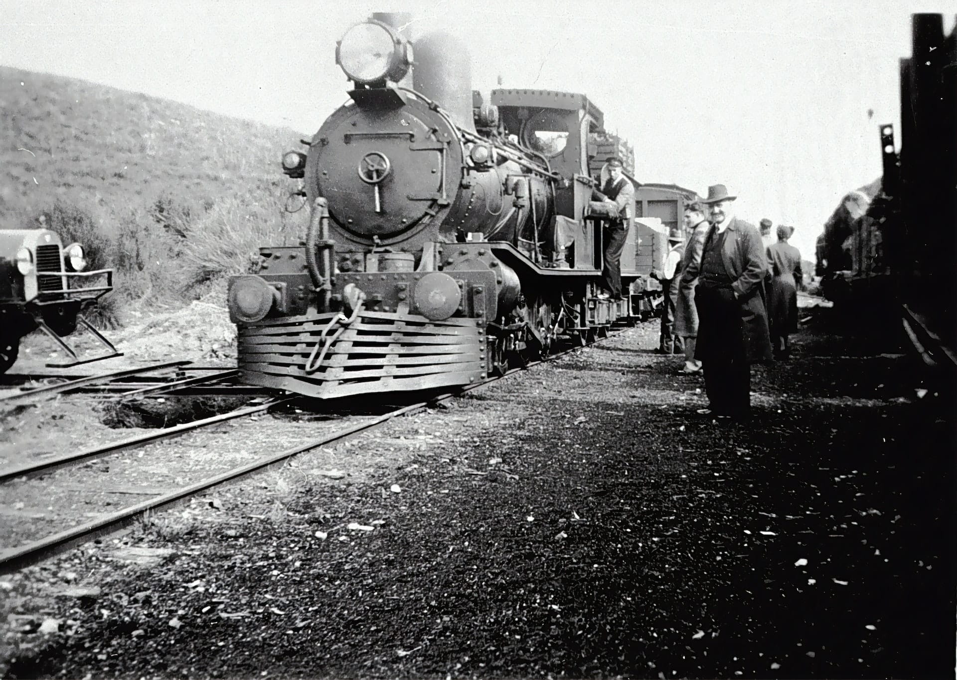 Eisenbahn fährt ein daneben steht Mann mit Hut