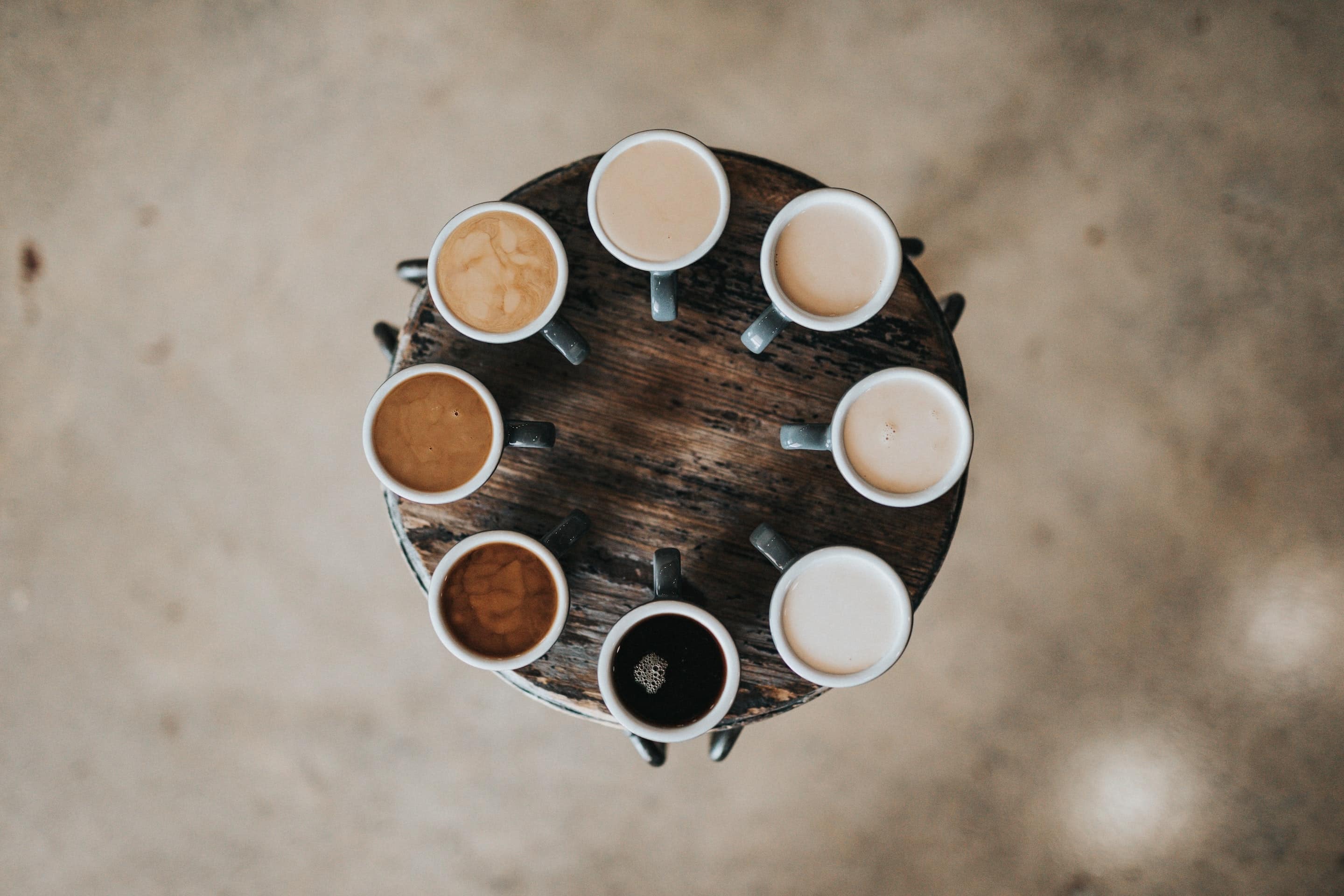 Verschiedene Kaffeetassen stehen im Kreis auf einem Tischchen