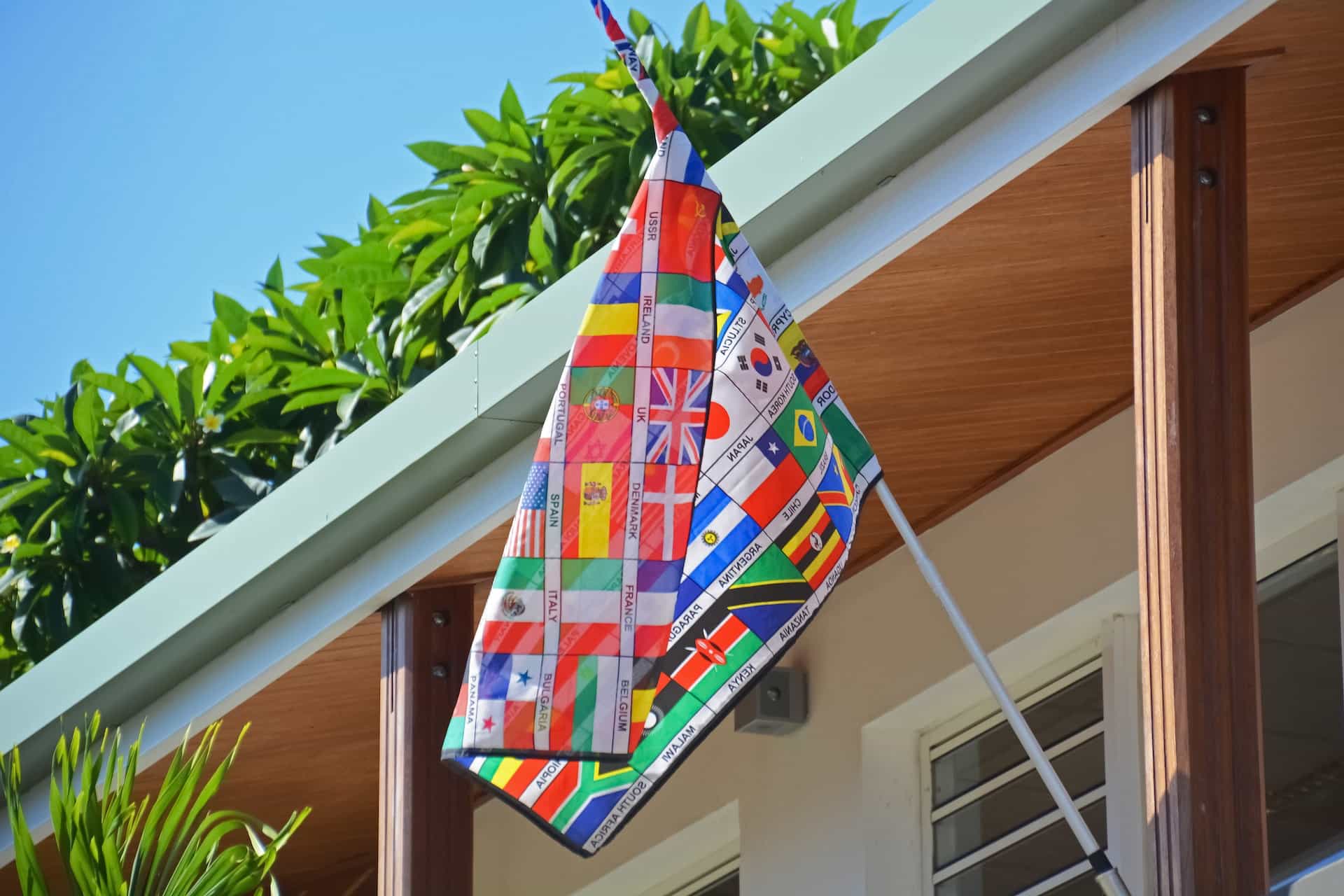 Eine Flagge aus verschiedenen Weltflaggen hängt an einer Hauswand.
