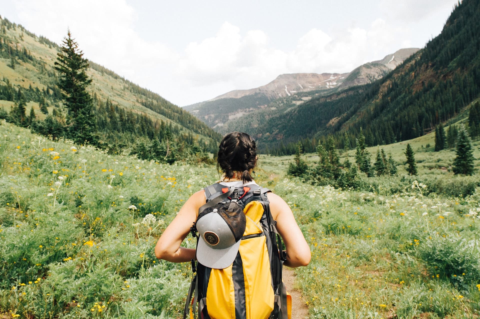Mädchen mit Zöpfen und Rucksack wandert in Berglandschaft