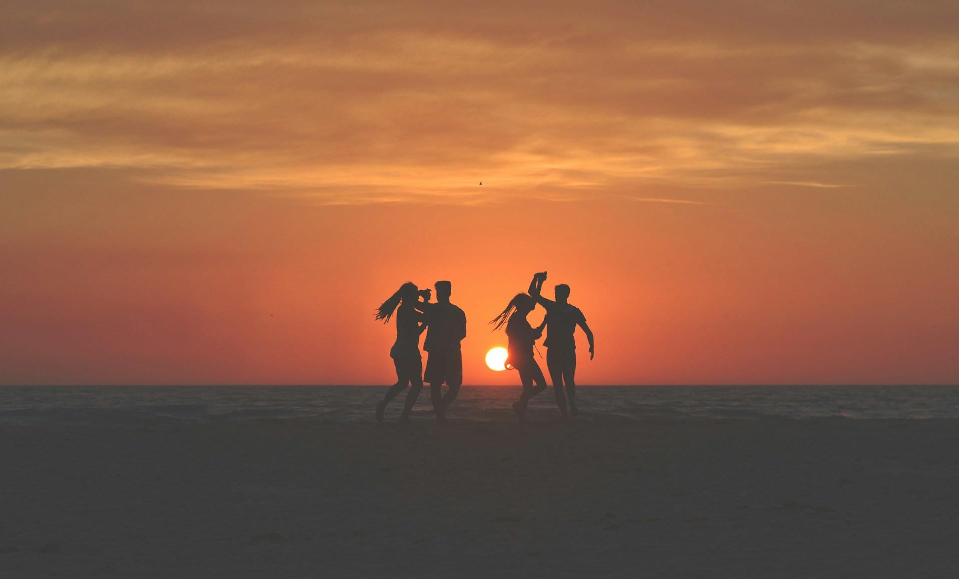 Zwei Paare tanzen am Strand im Sonnenuntergang