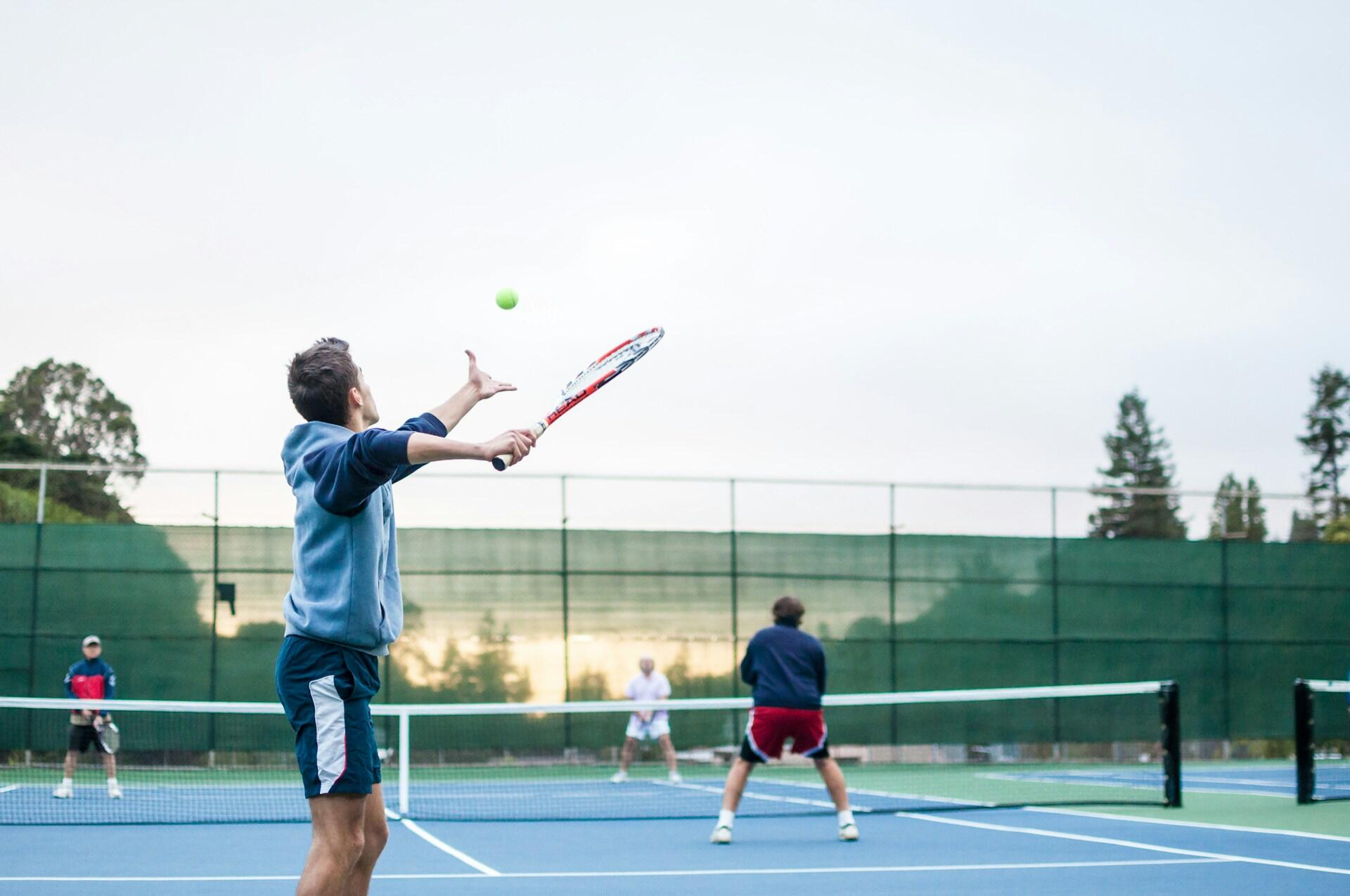 vier Menschen spielen Tennis