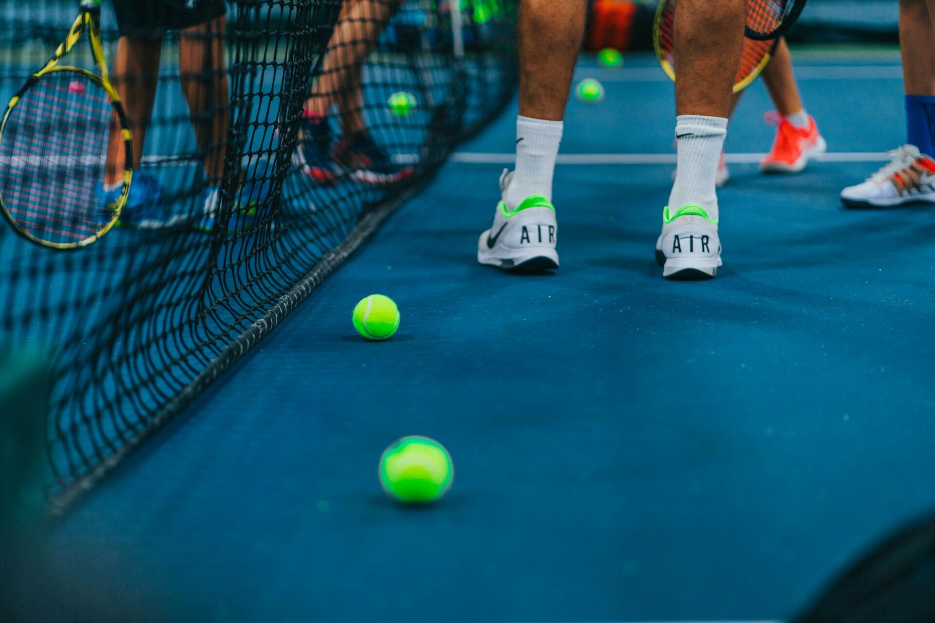 Mehrere Menschen stehen in Sportsachen am Tennisnetz