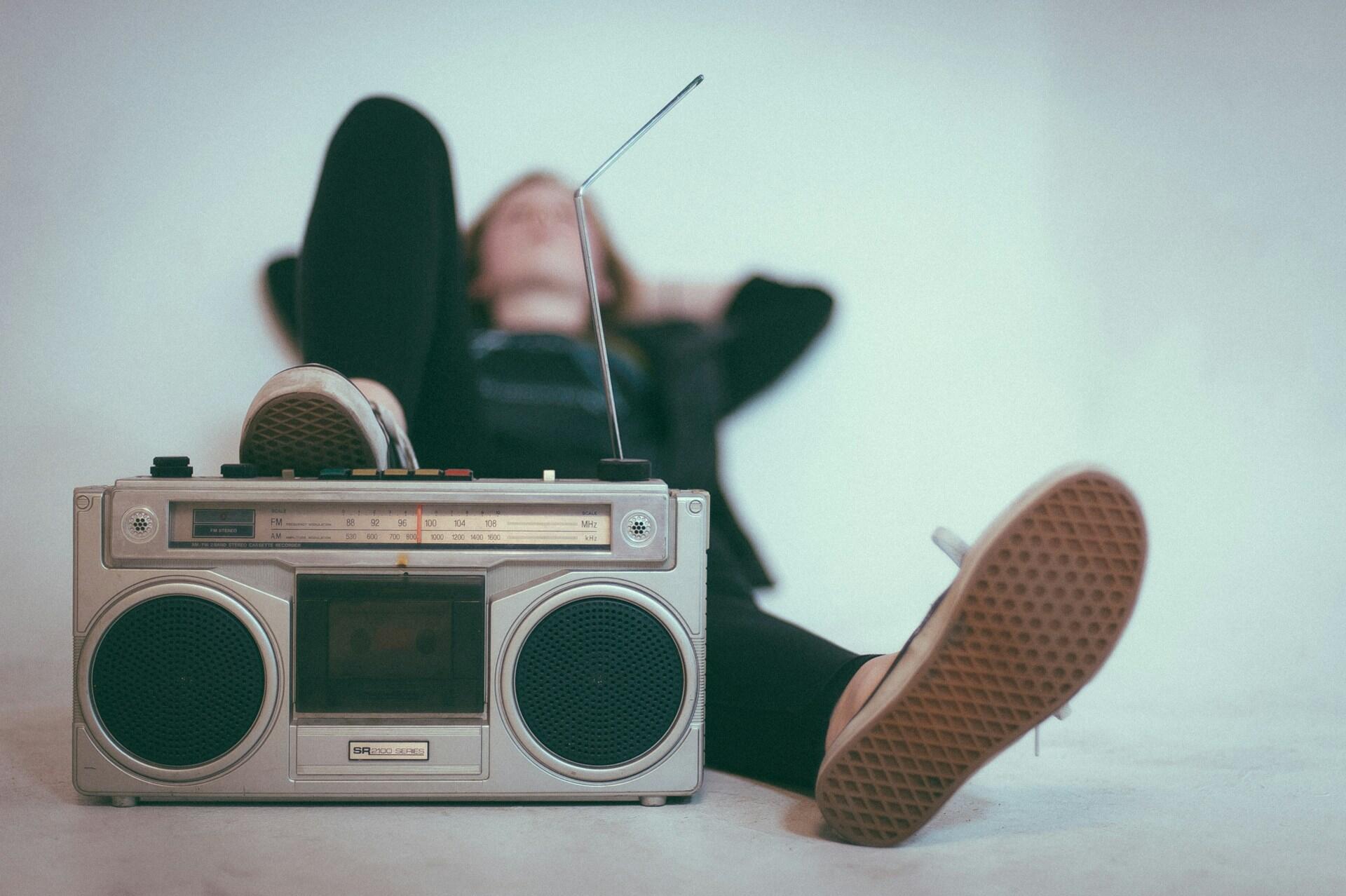 Frau liegt und hört Musik aus einem Radio