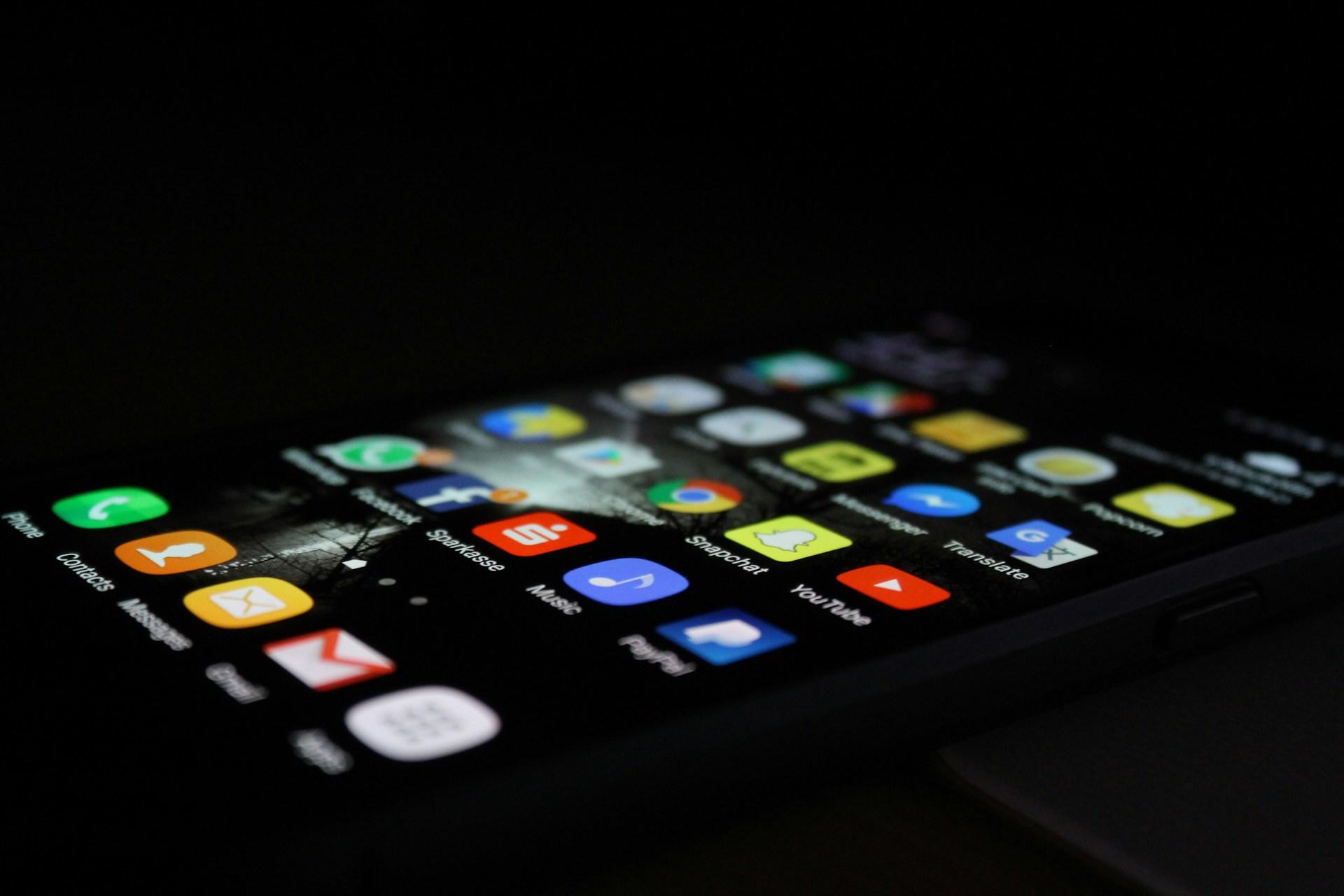 A smartphone screen full of colourful app icons against a black background, both on the phone and in the picture.