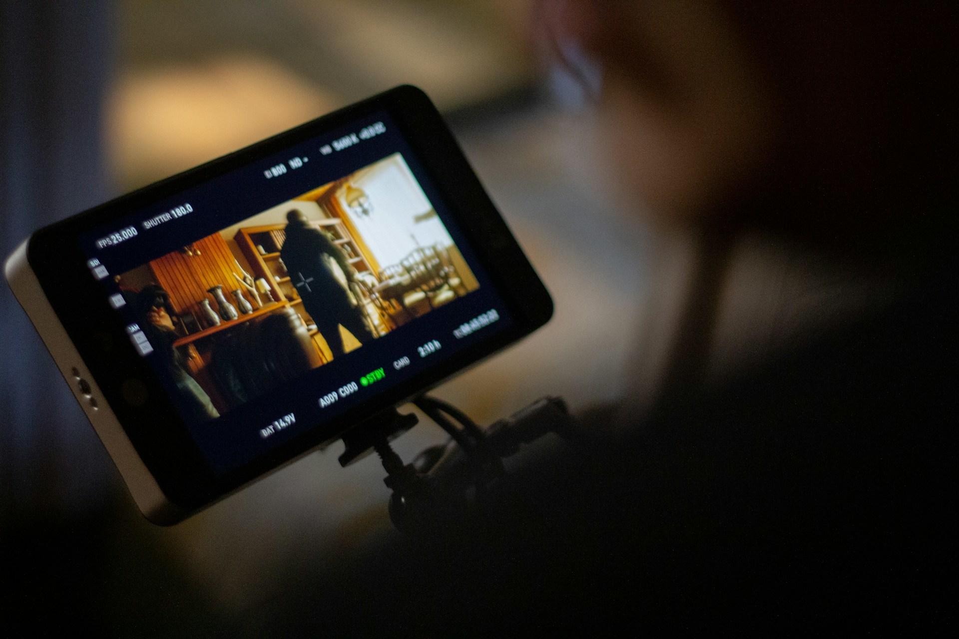 A small screen device display movie action on a small screen framed in black with various settings indicated with white lettering.