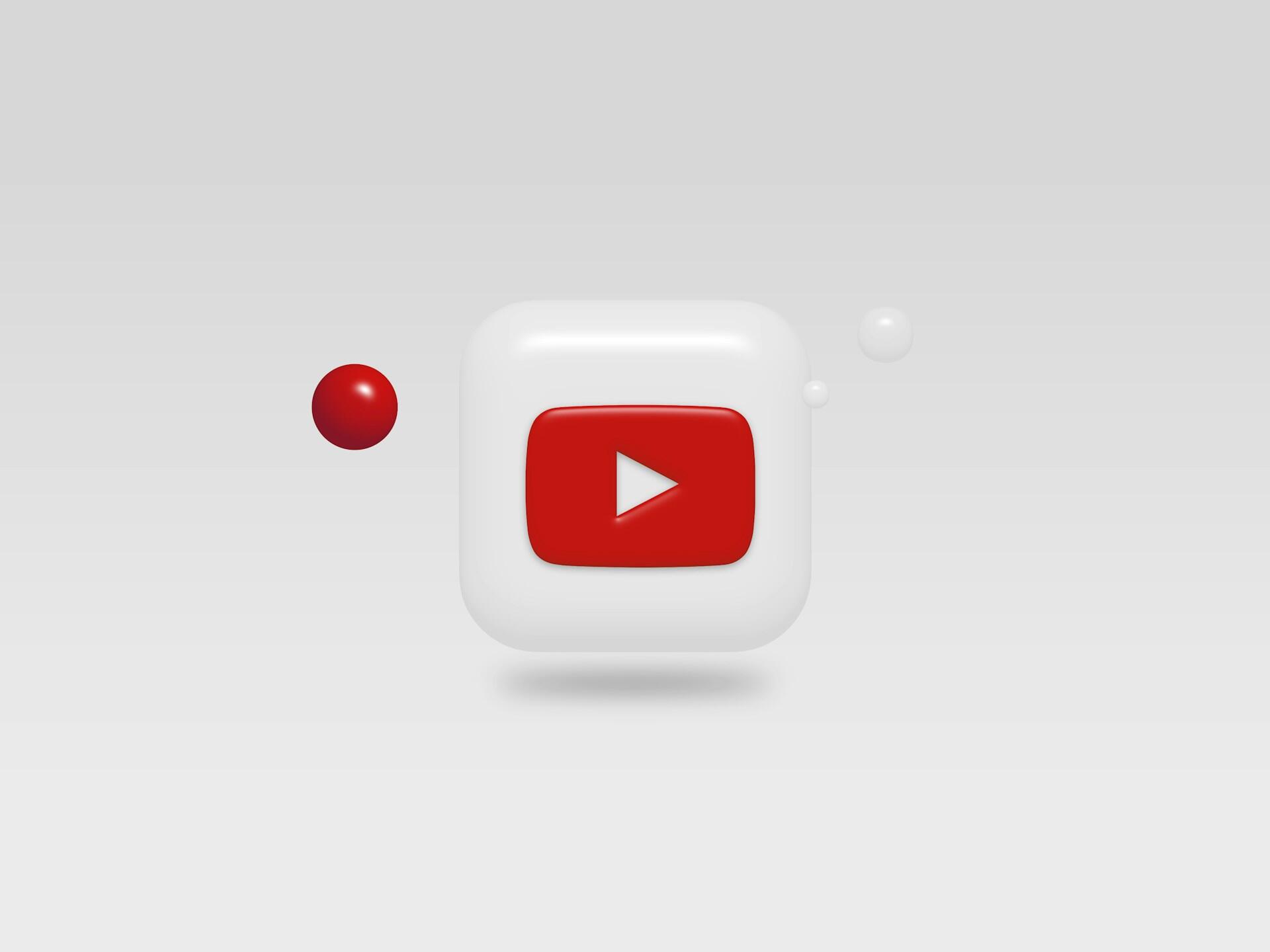 A stylized YouTube logo featuring a red play button on a white square, accompanied by two floating red and white spheres.