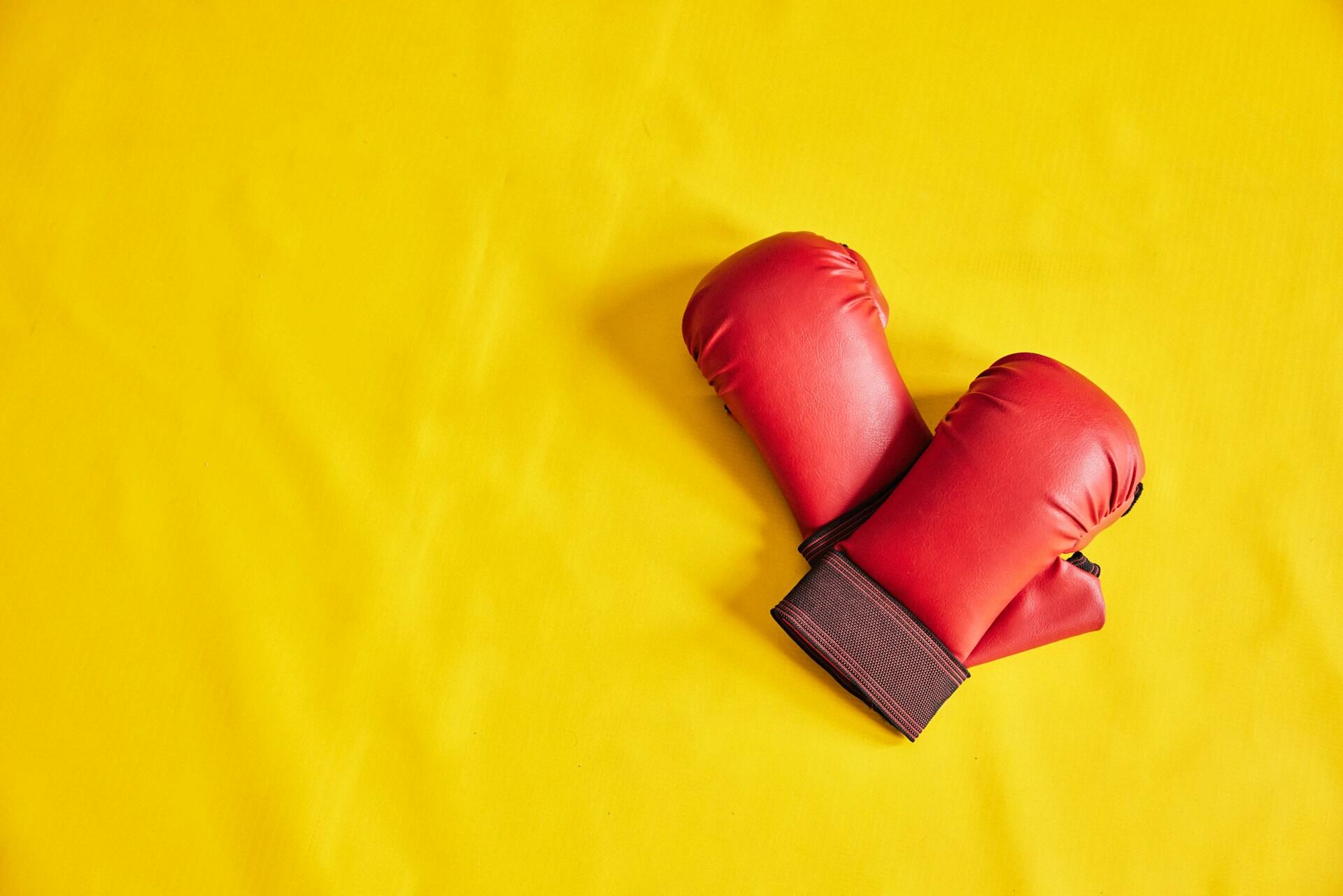 A pair of red boxing gloves on a yellow background.