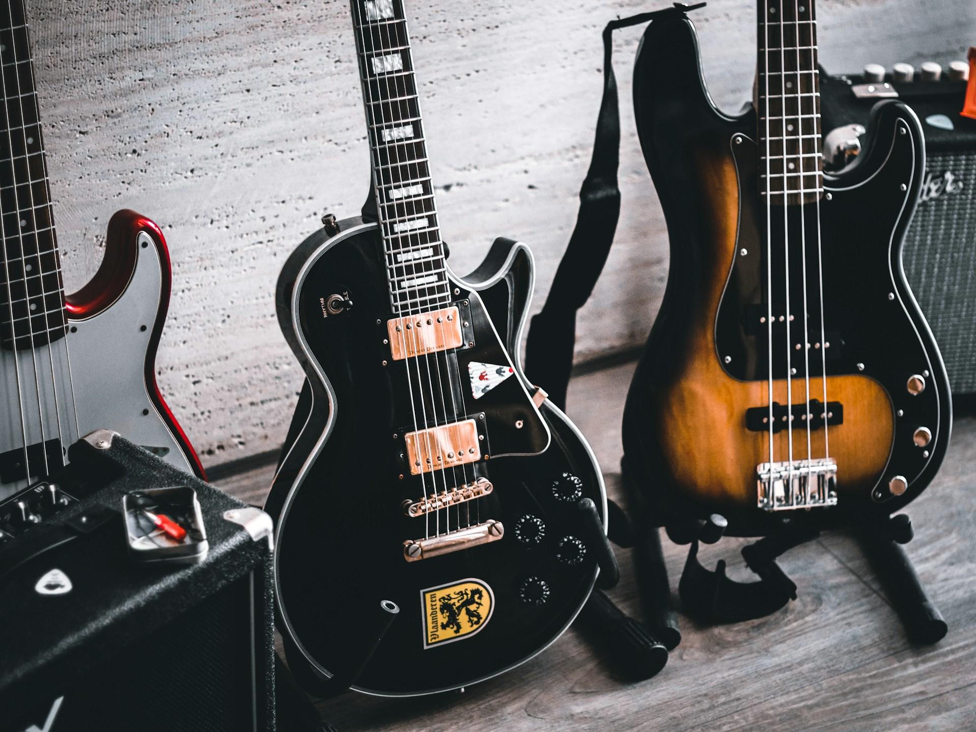 Three guitars resting on a wooden floor