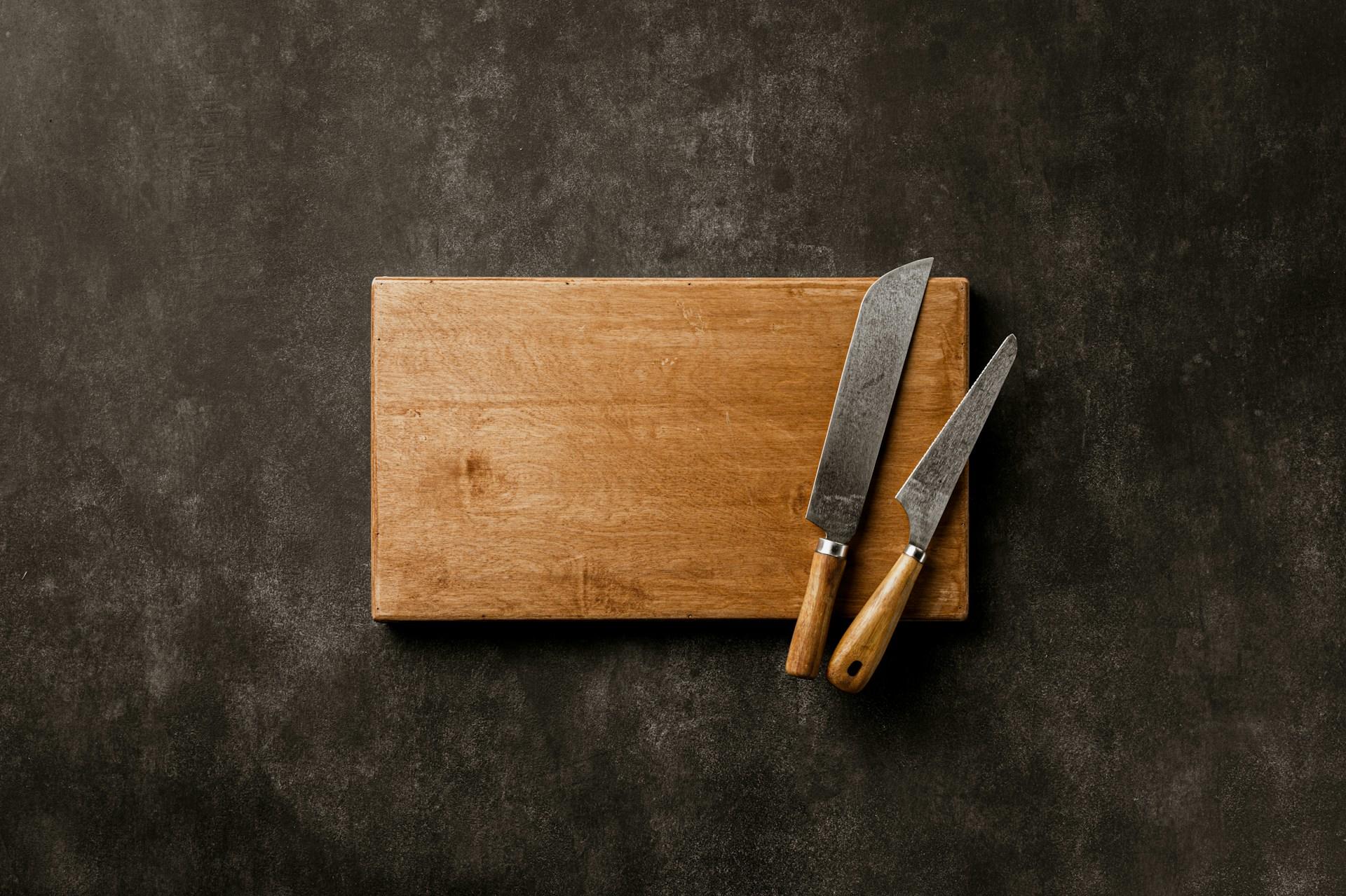 A cutting board and two knives on it.