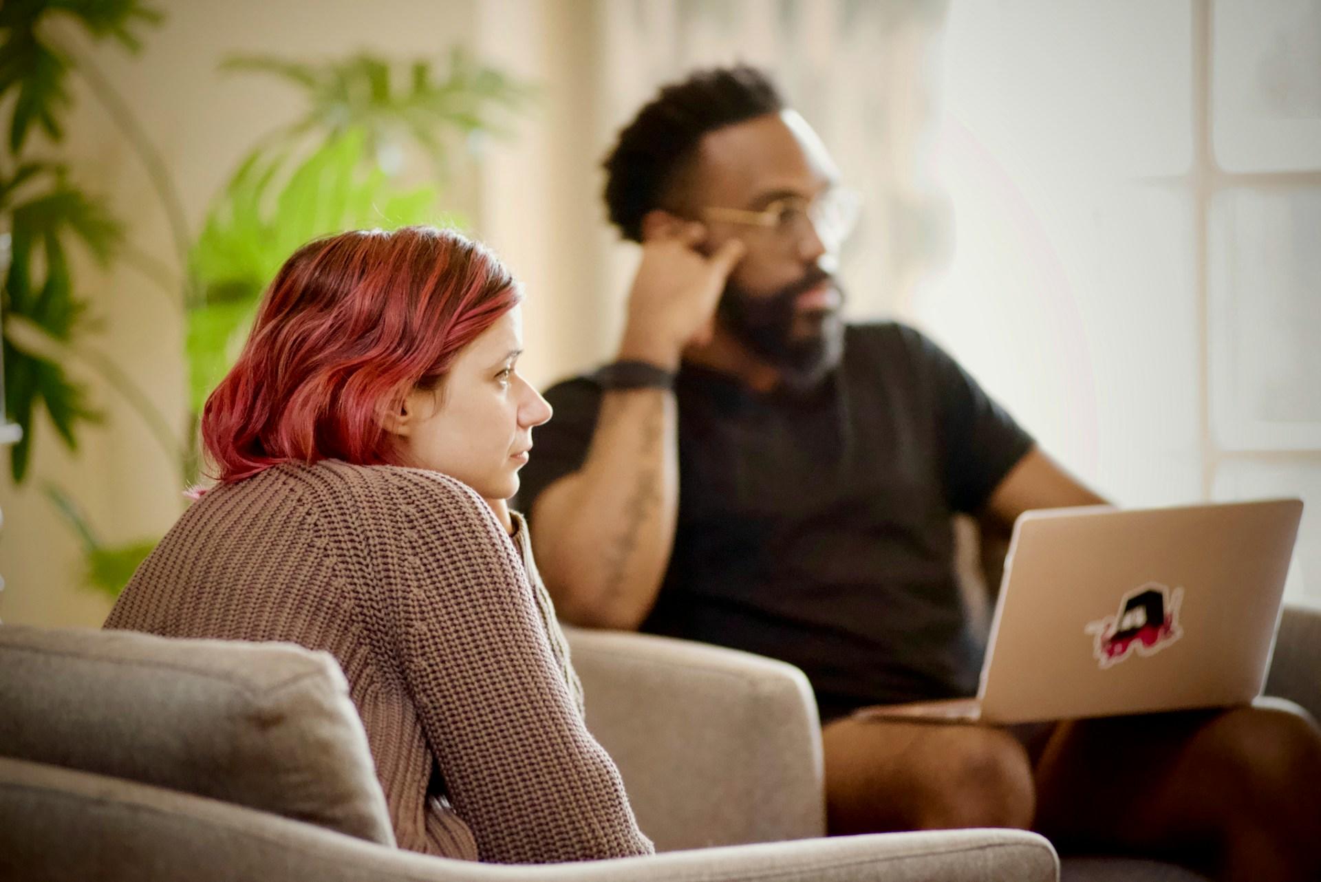 two people sitting on a couch, listening to a conversation