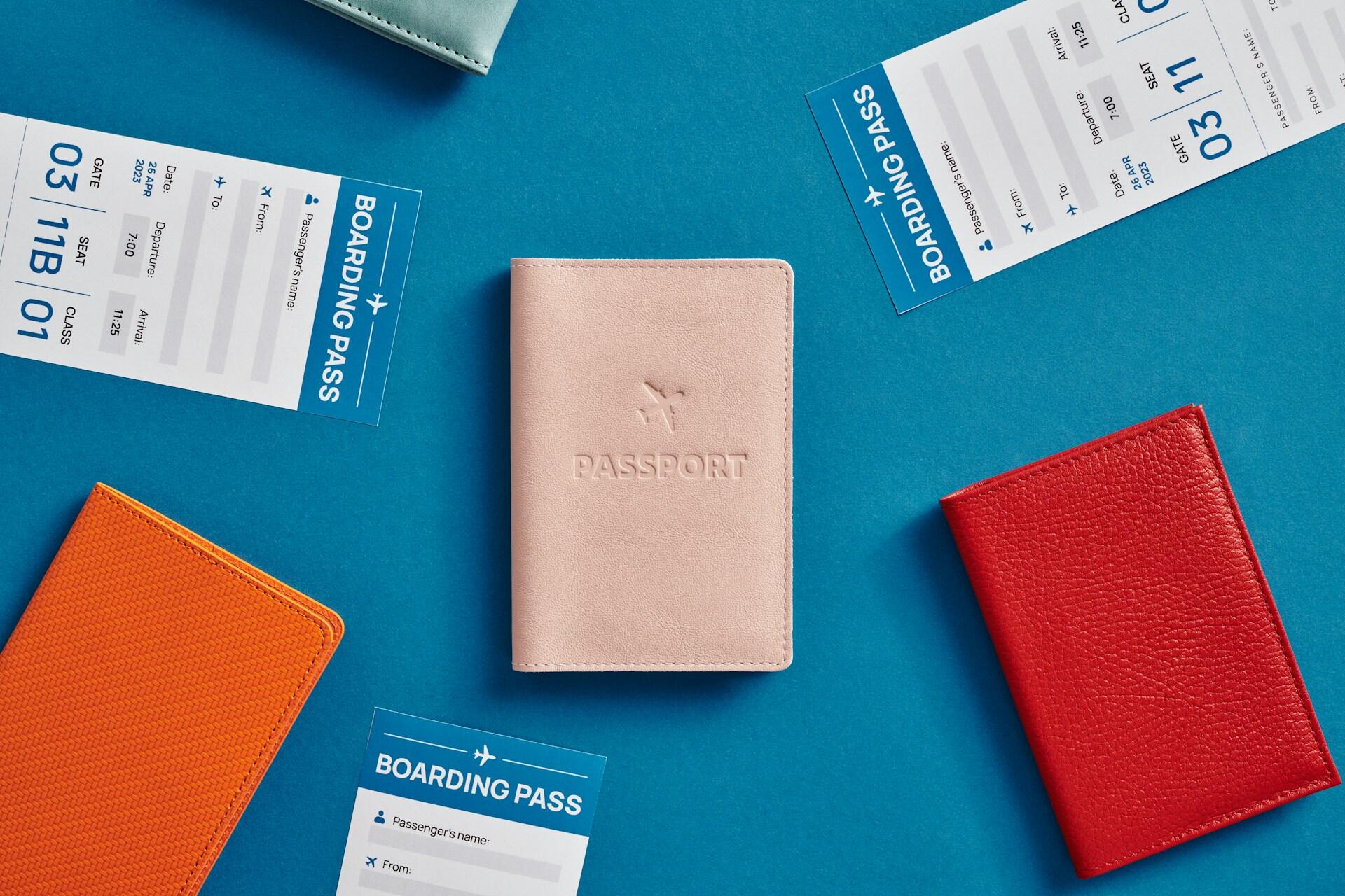 A pink passport holder surrounded by colorful passport holders and boarding passes on a blue background.