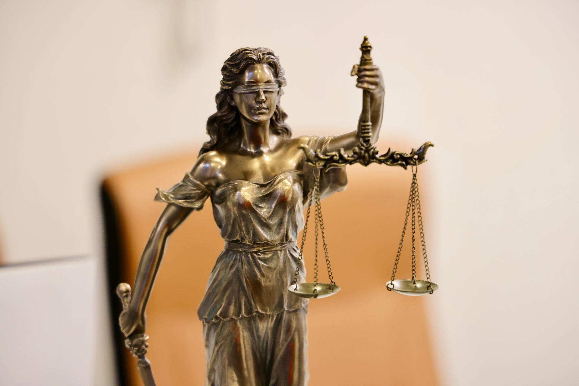 a gold statuette of Justice with a blindfold and holding scales